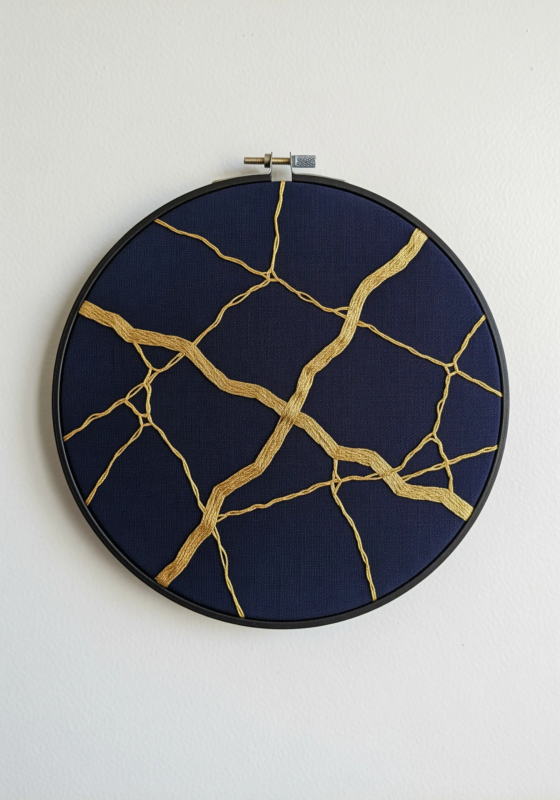Gold metallic thread stitched in a Kintsugi-style crack pattern on a dark blue background.