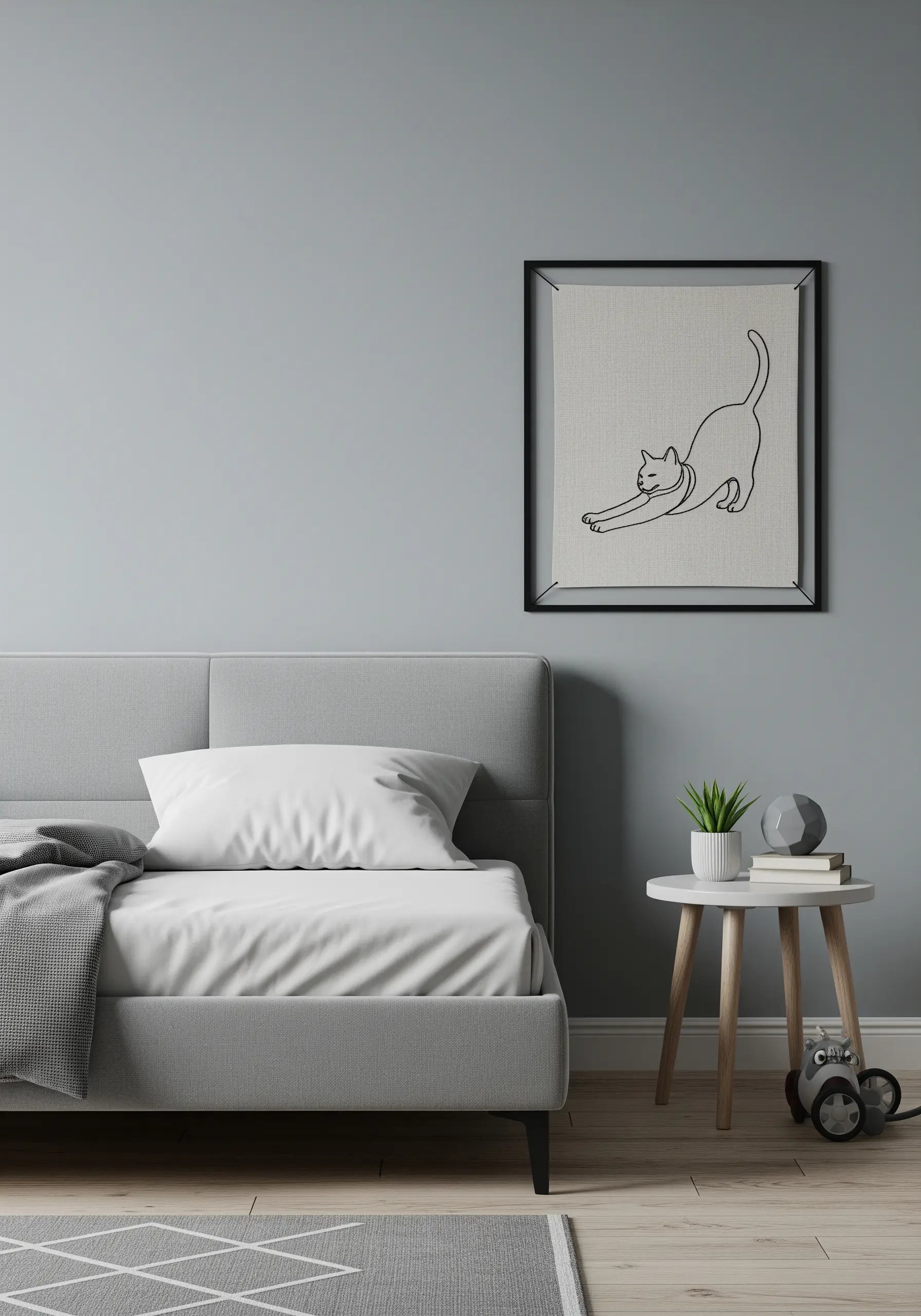 Minimalist line art embroidery of a stretching cat, stitched in black thread and displayed in a black frame.