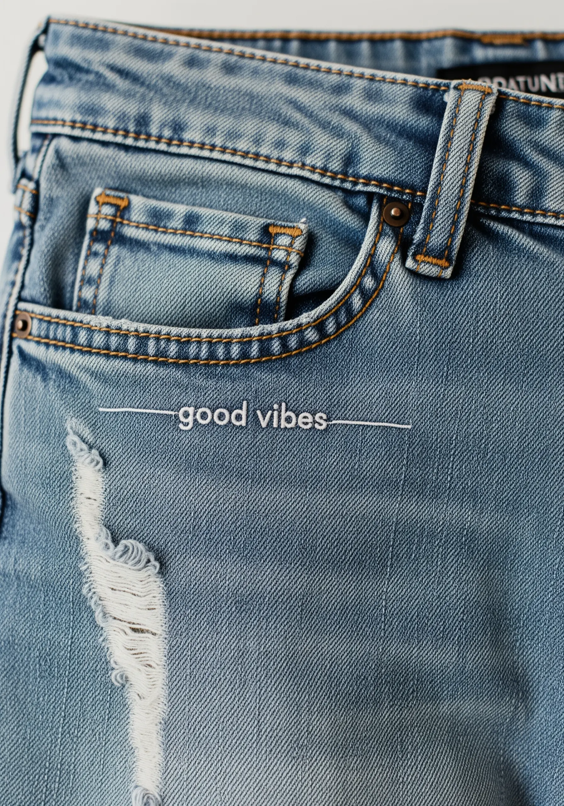 Minimalist 'good vibes' embroidered in fine white thread on jeans