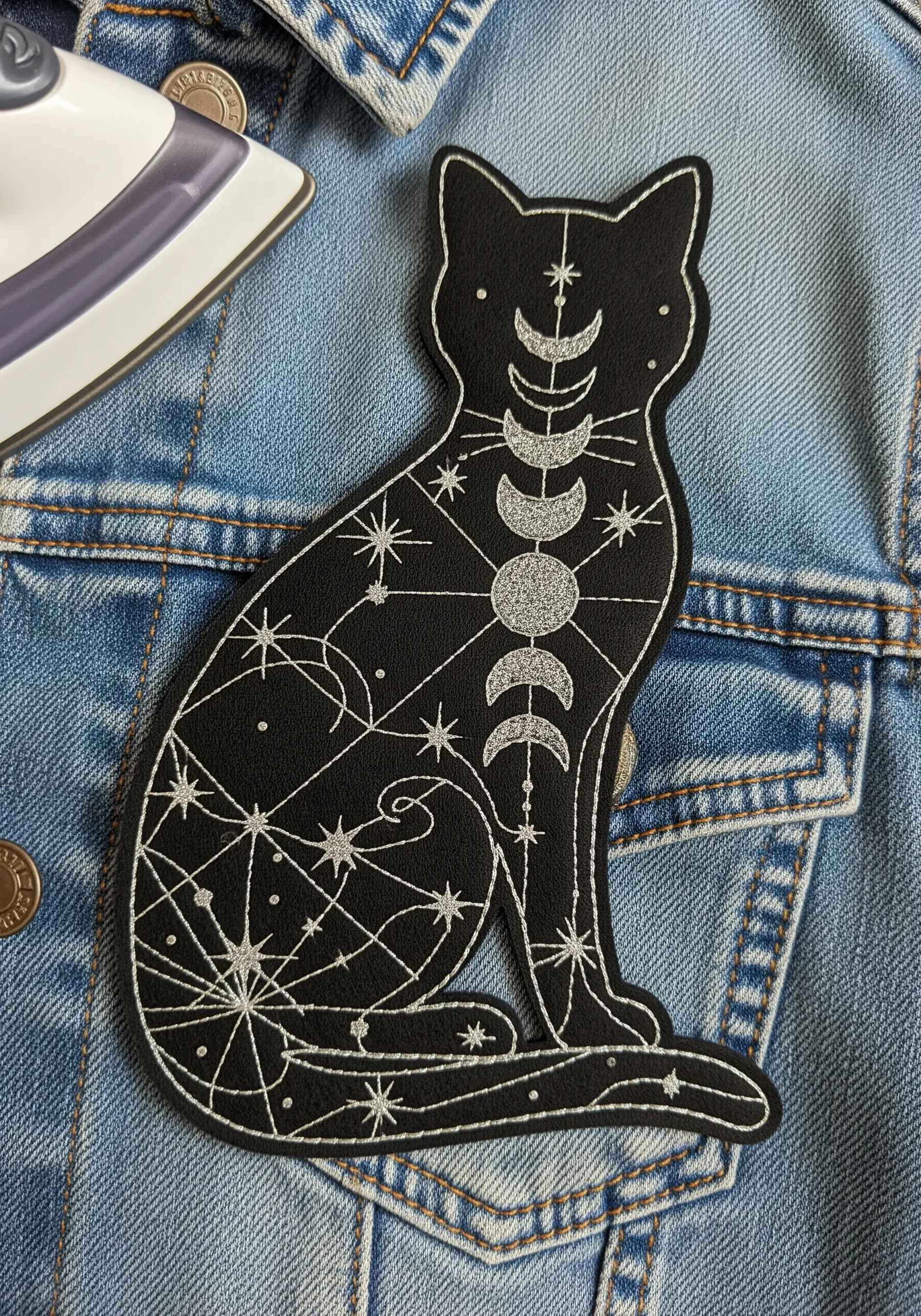 A black faux leather patch of a celestial cat with moon phases.