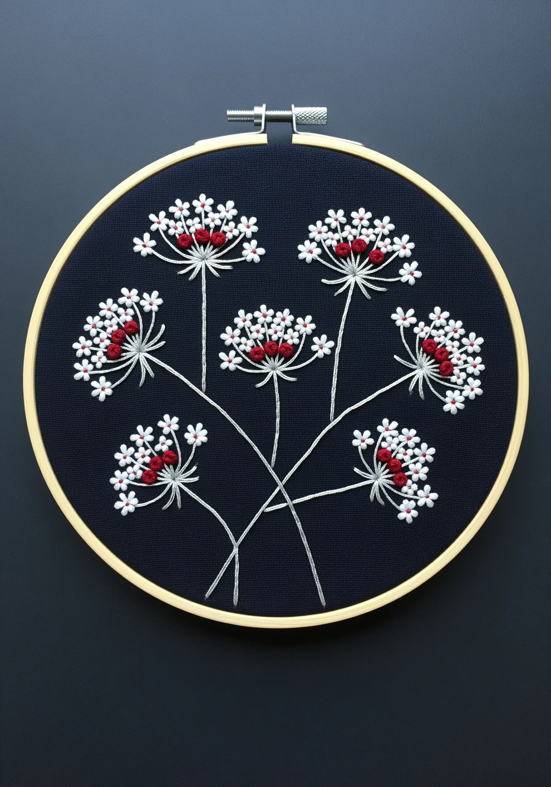 Delicate Queen Anne's Lace embroidered with white and red stitches on dark navy blue fabric.