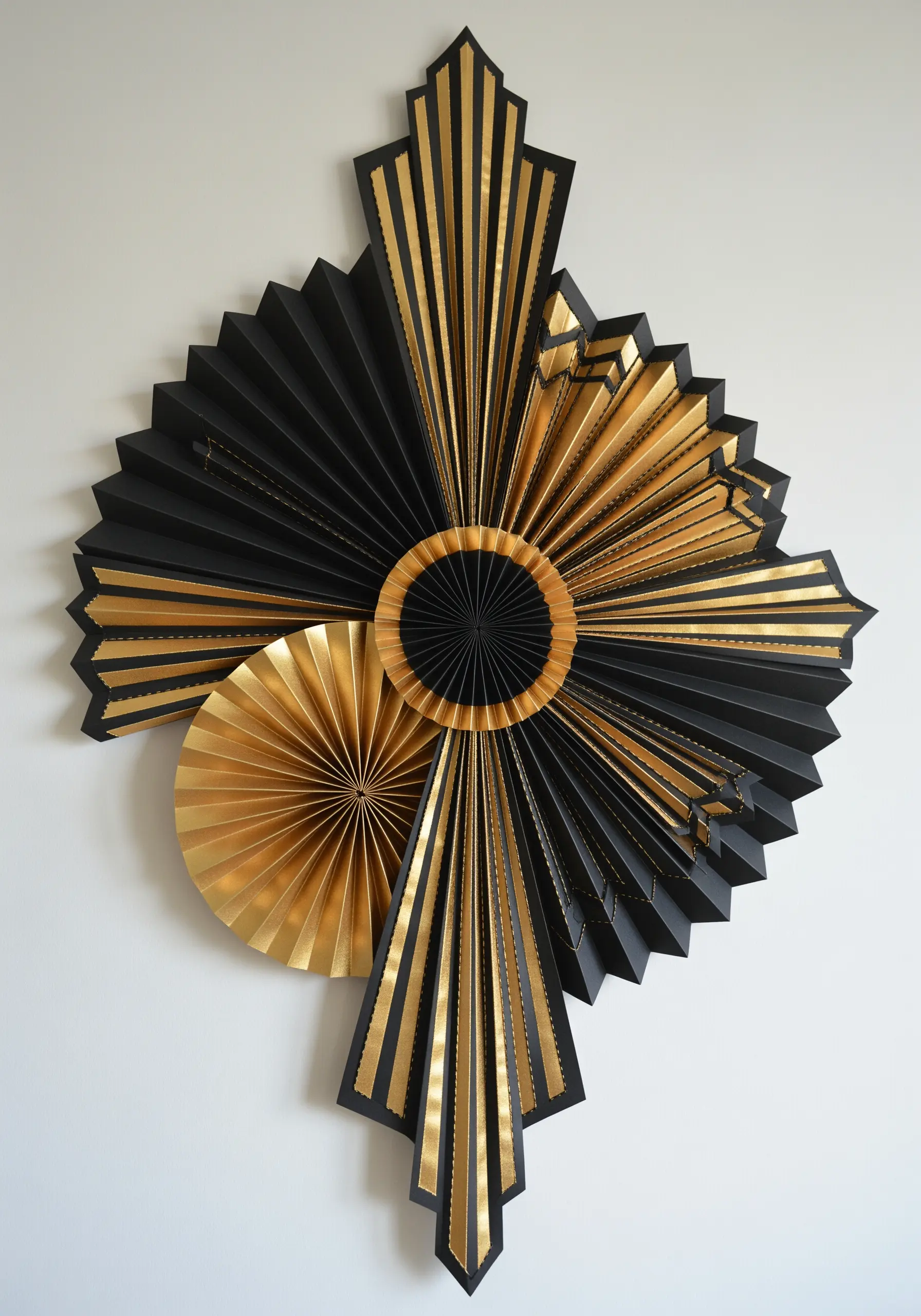 An abstract Art Deco-style wall sculpture made from black and gold folded paper fans.