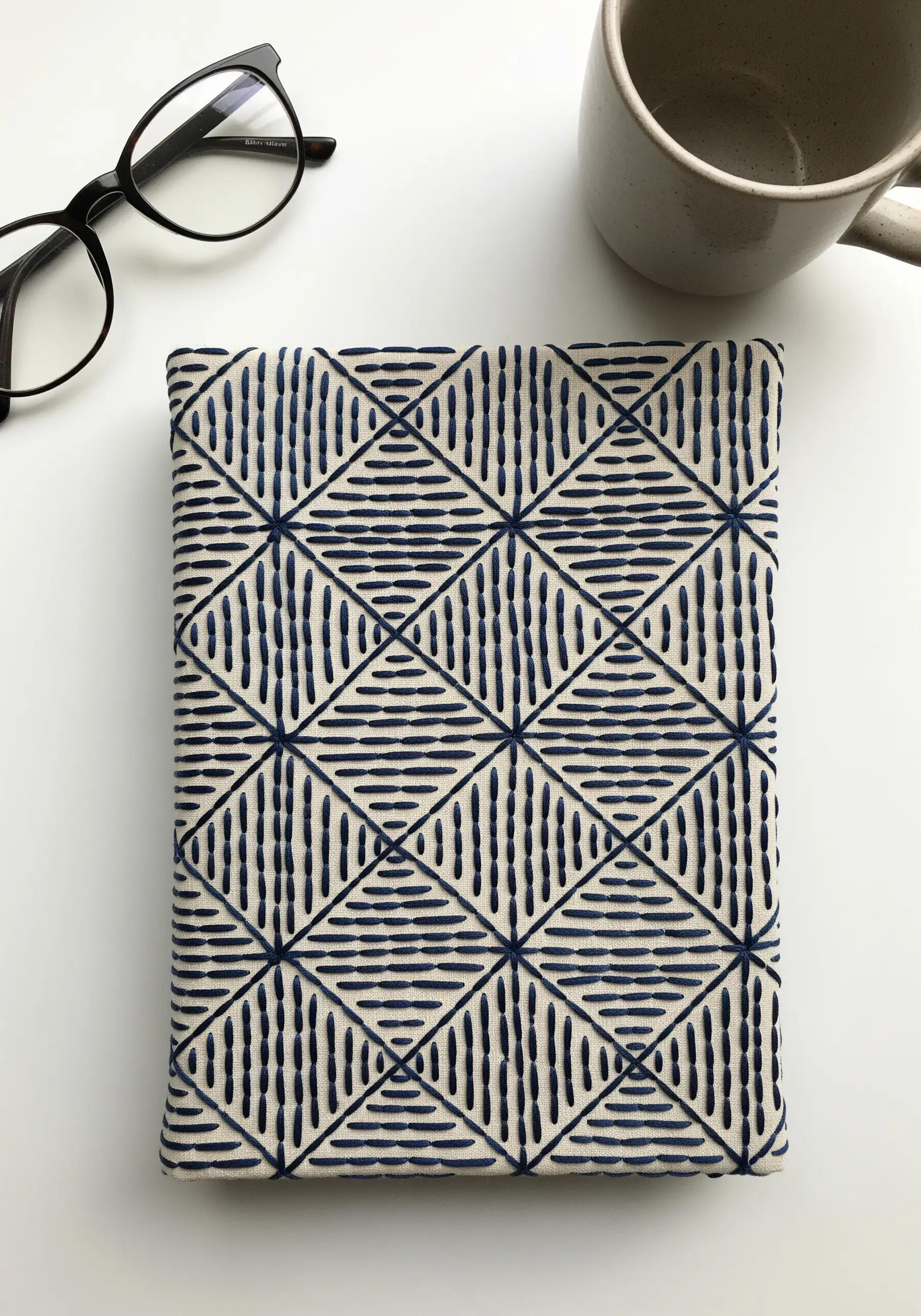 A fabric-covered book with a geometric diamond pattern stitched in dark blue thread.