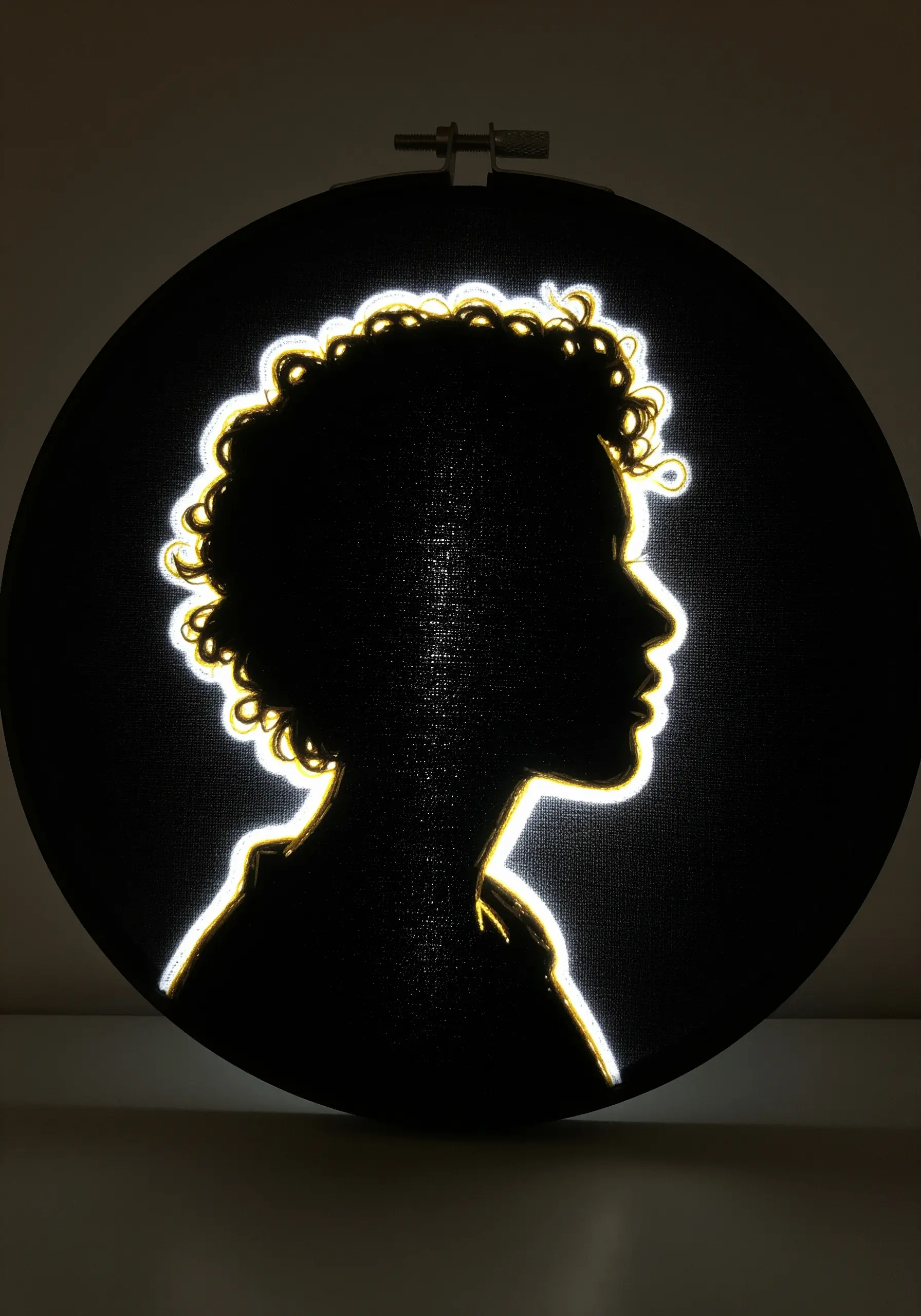 Embroidered silhouette of a person with a bright, glowing outline on black fabric.