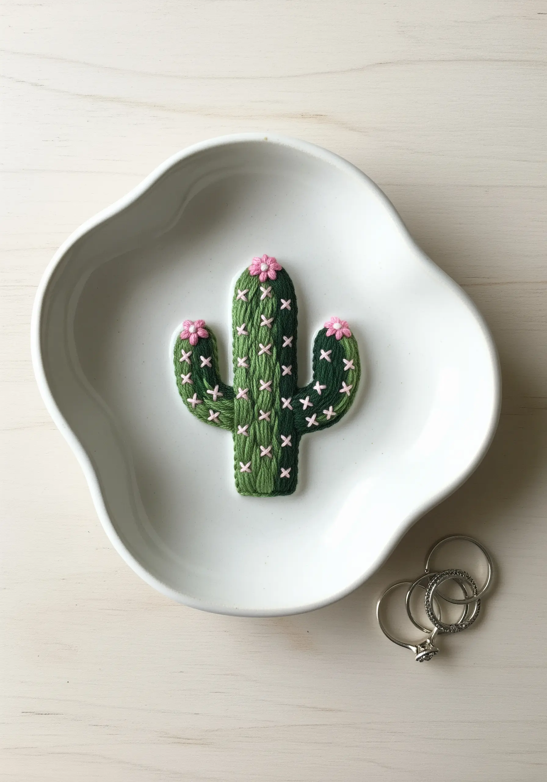 Freestanding 3D embroidered cactus with pink flowers in a white dish.