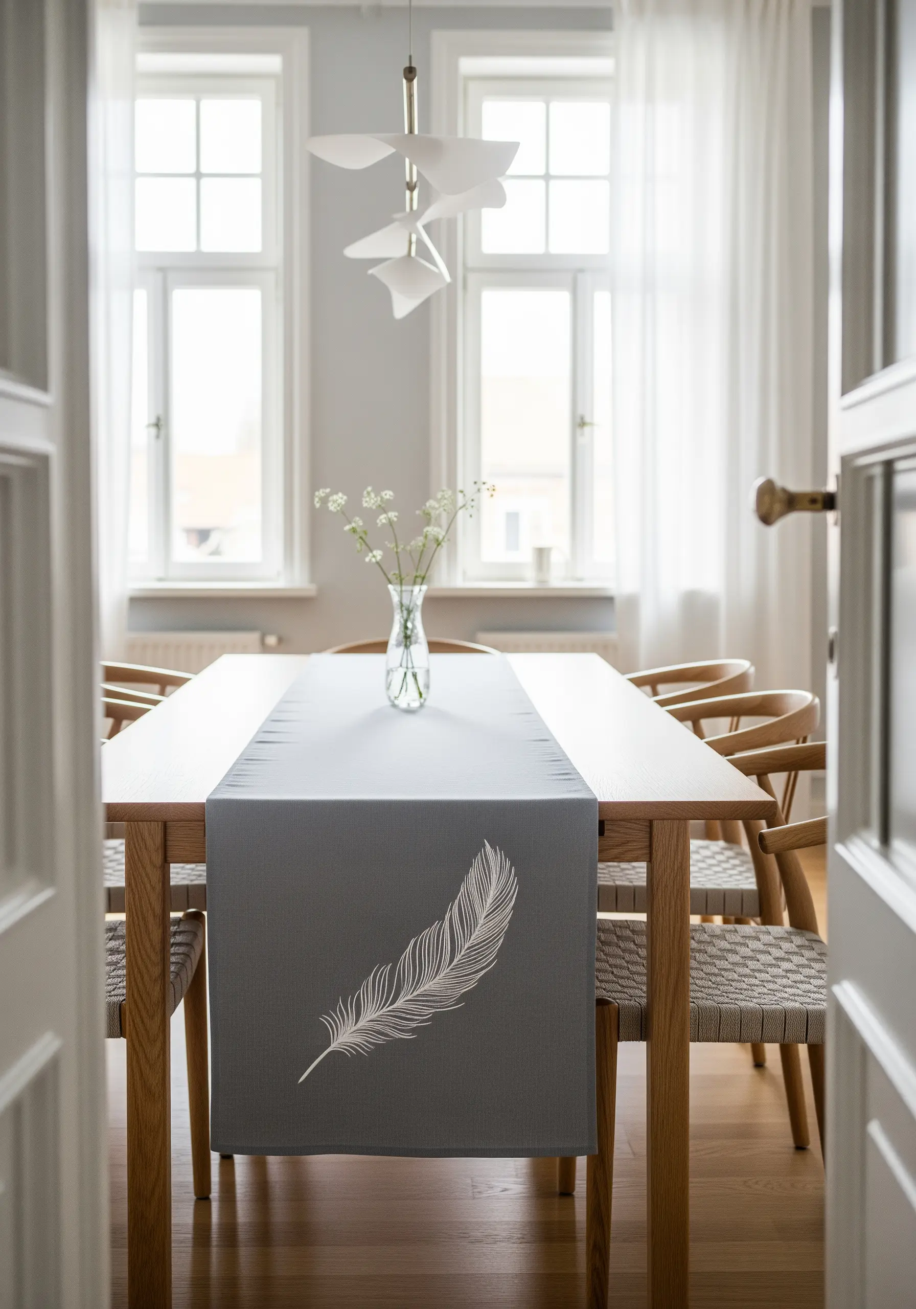 A single, delicate white feather embroidered on a dark gray table runner