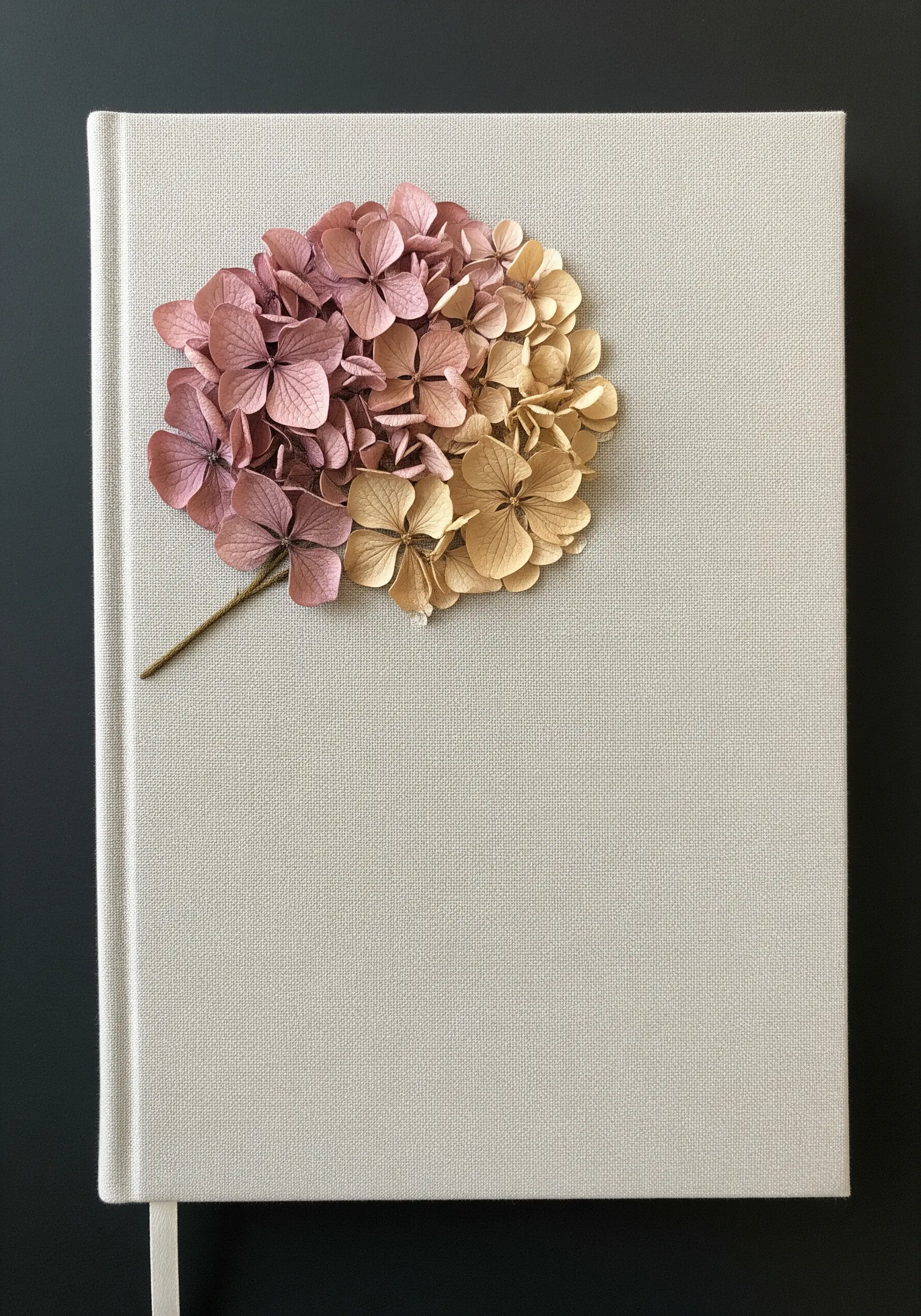 A dried-look hydrangea in muted pink and beige tones on a linen journal cover.