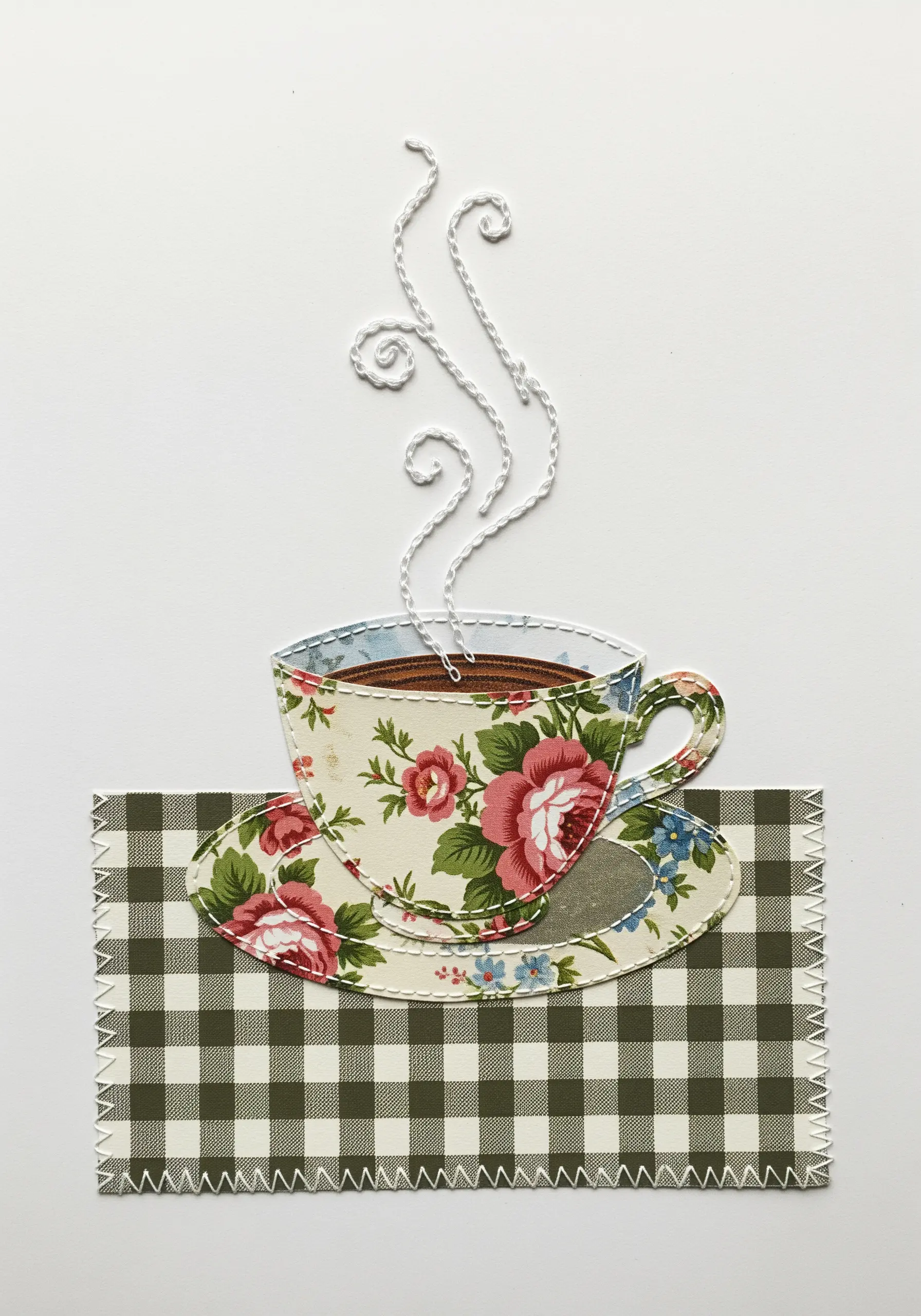 A fabric collage teacup with white thread swirling above it to represent steam.