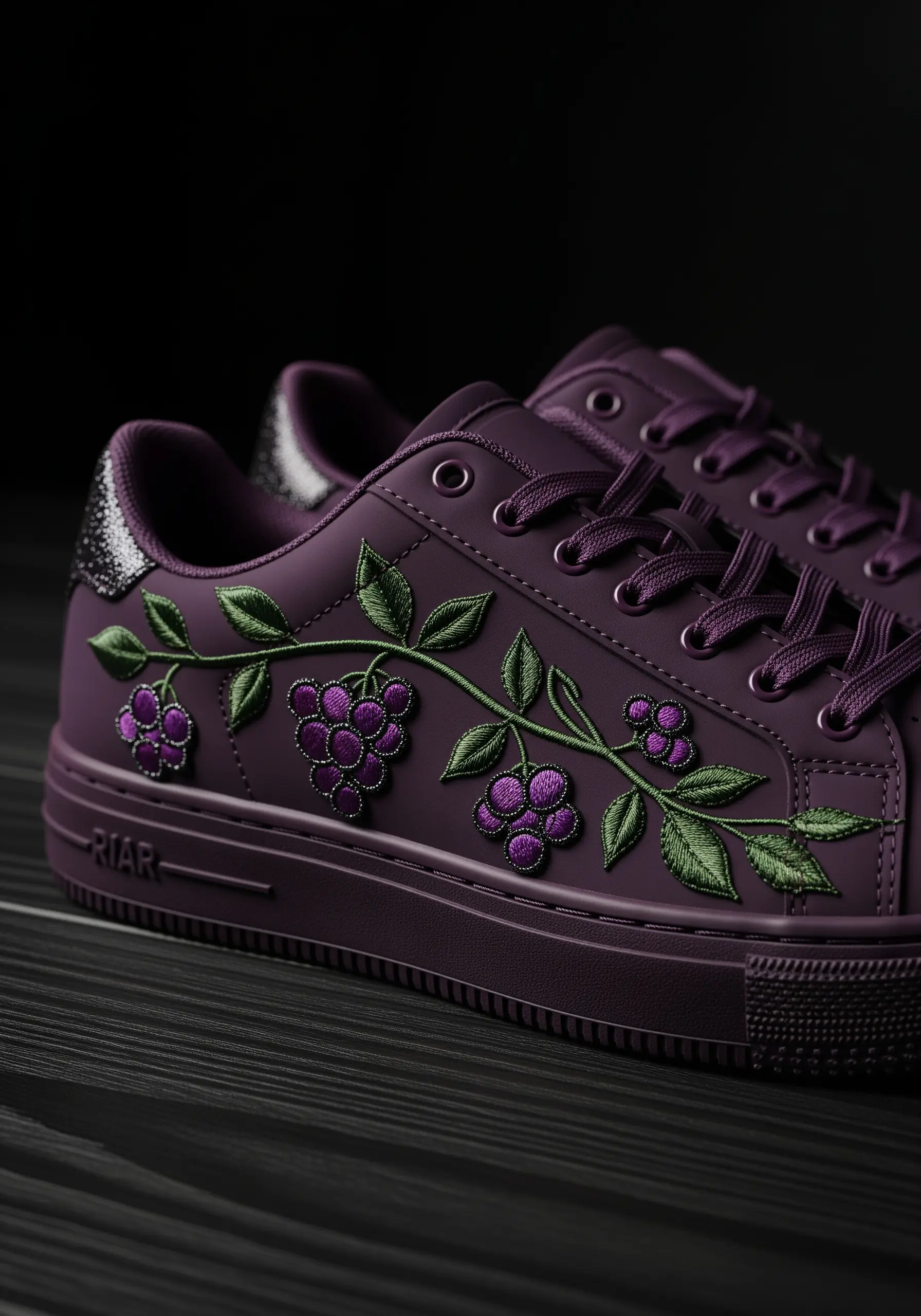 A tone-on-tone embroidery of a berry vine in purple thread on a purple sneaker.