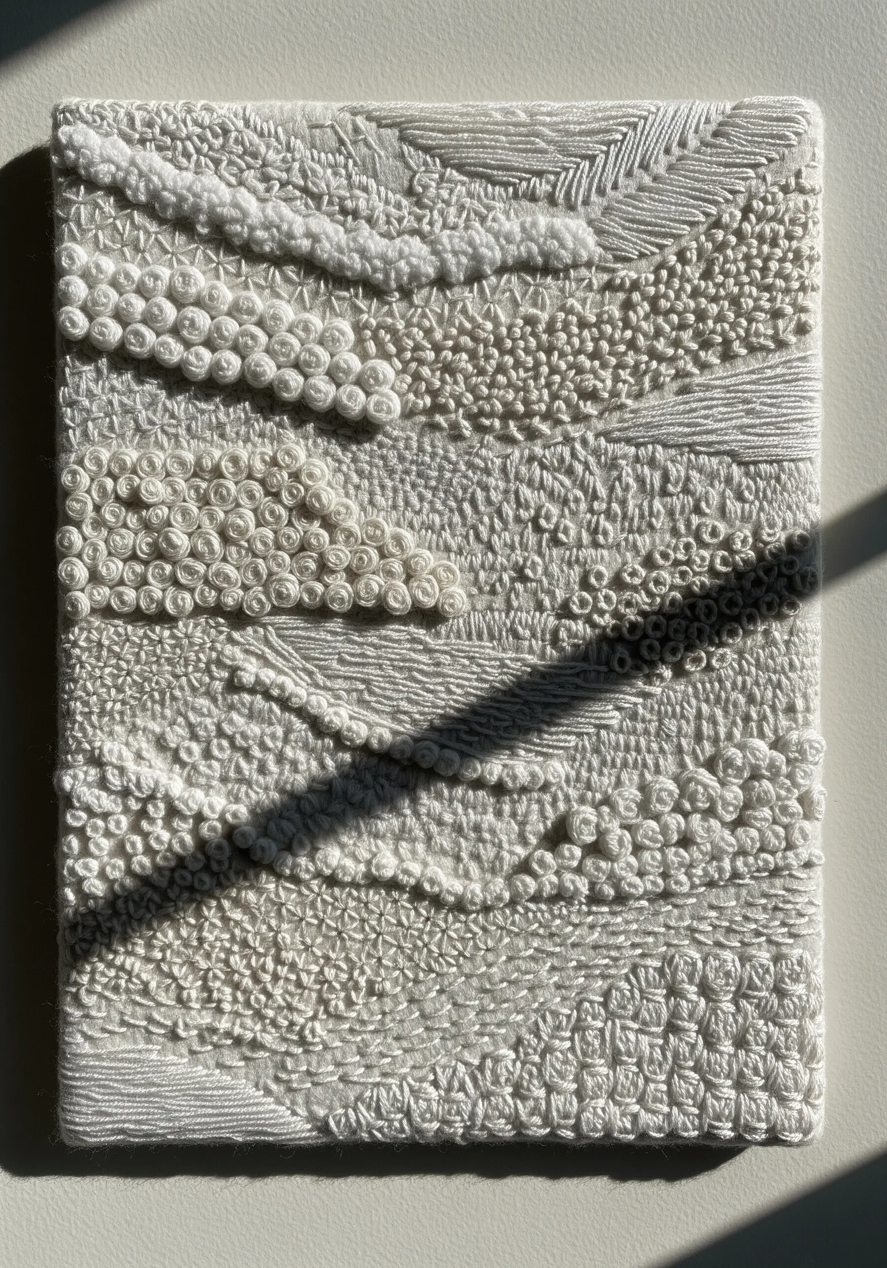 Monochrome white textural embroidery with French knots, satin stitch, and woven wheels.