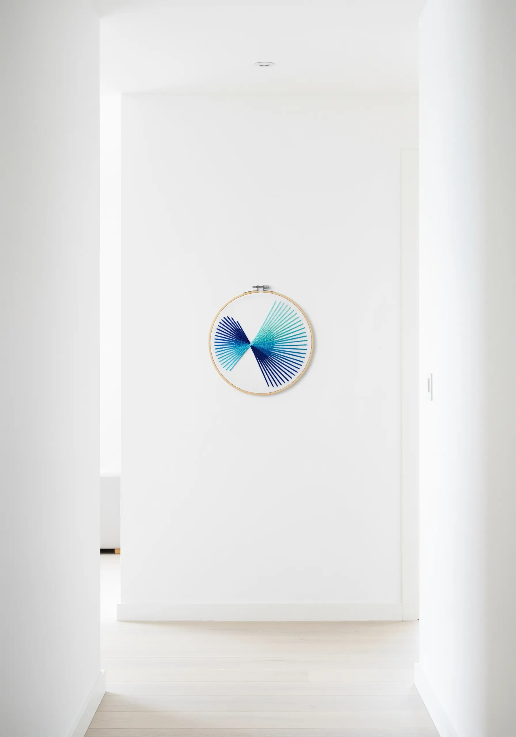 Radiating straight stitches in a gradient of blue and green on a white hoop.