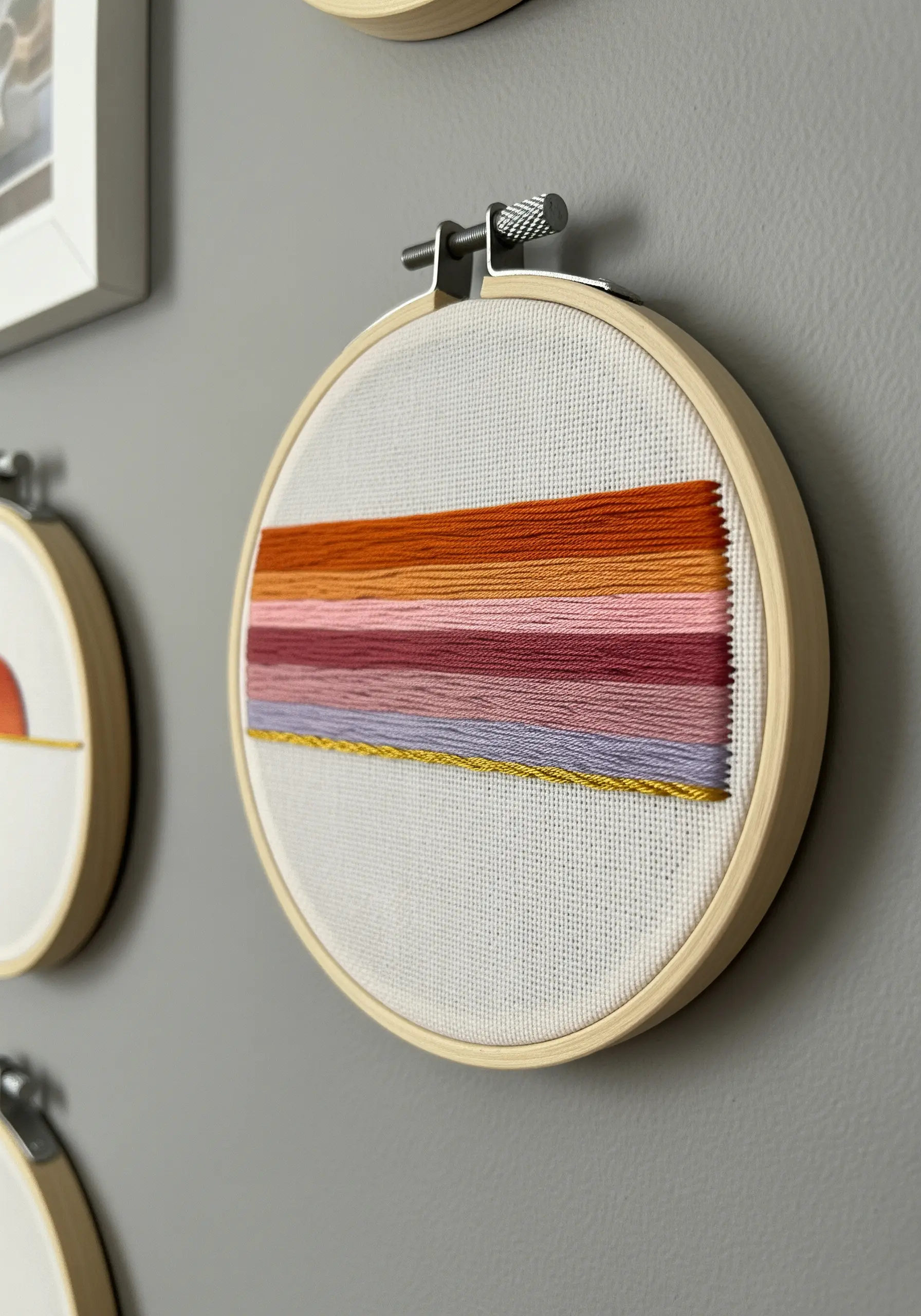 Abstract embroidery hoop with horizontal blocks of color in a sunset-inspired gradient.