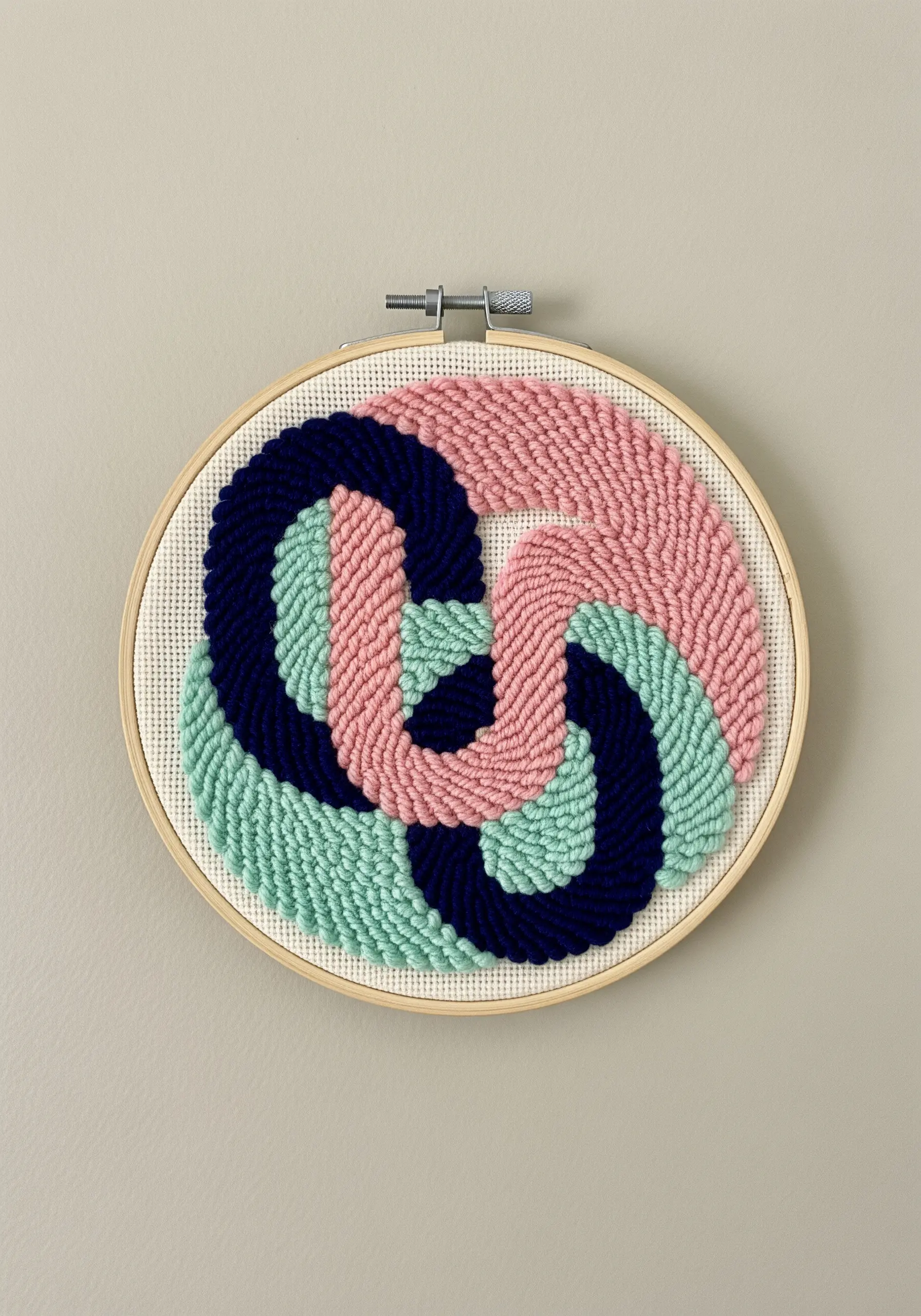 Abstract punch needle art in a hoop with interlocking pink, blue, and navy shapes.