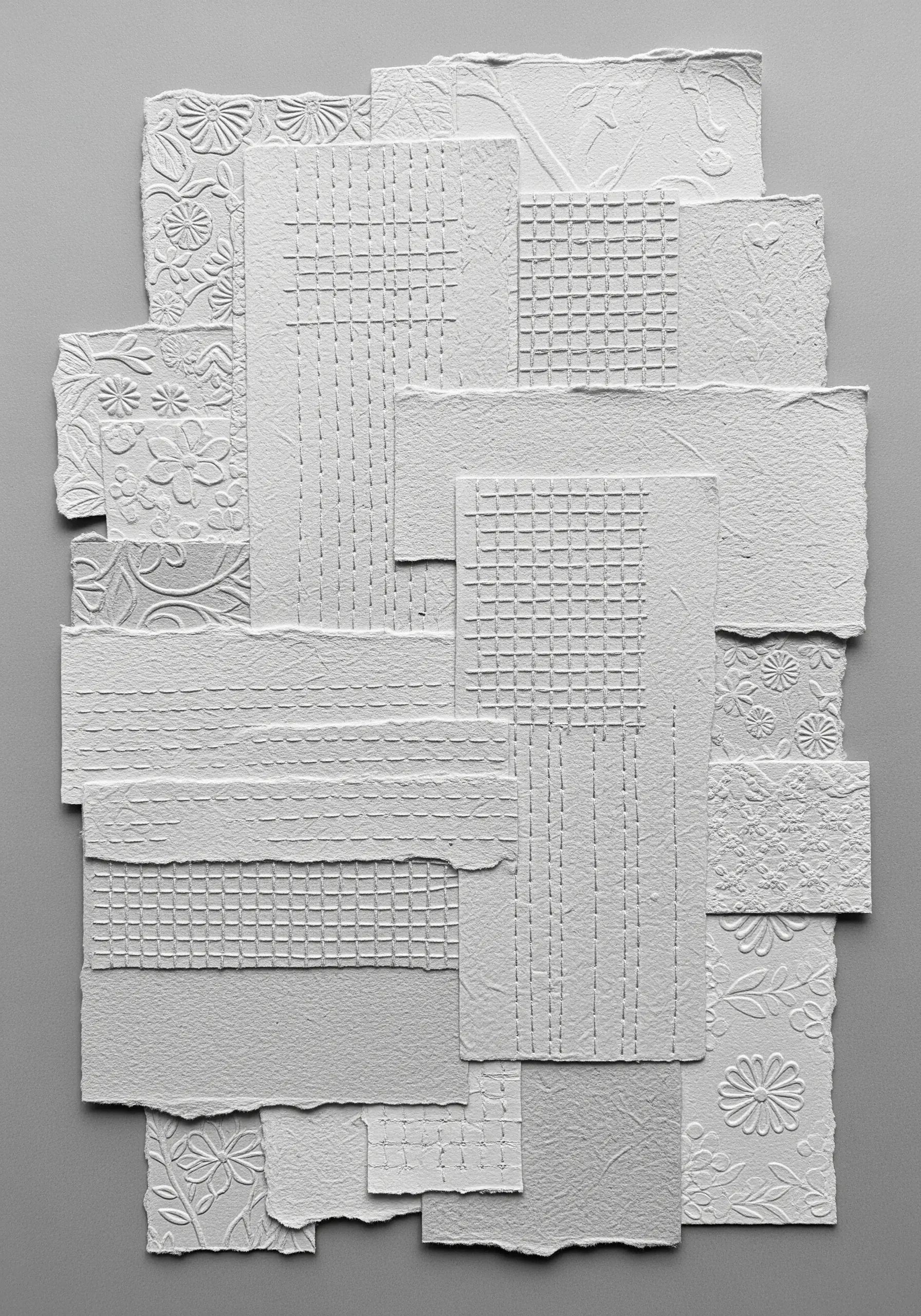 A monochrome white collage of layered embossed and stitched paper, creating a subtle textural landscape.
