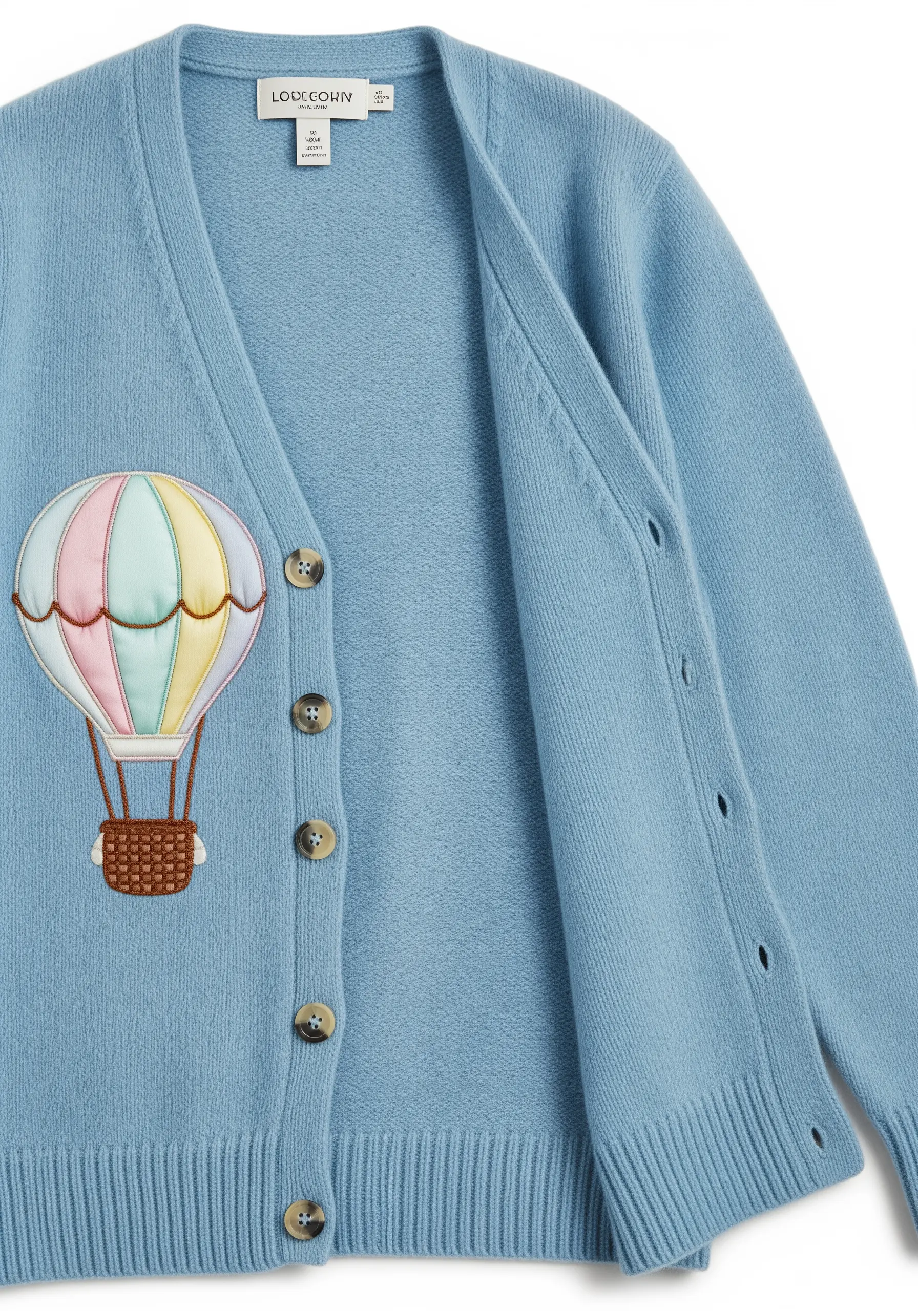 Hot air balloon appliqué with pastel fabric panels on a blue cardigan.