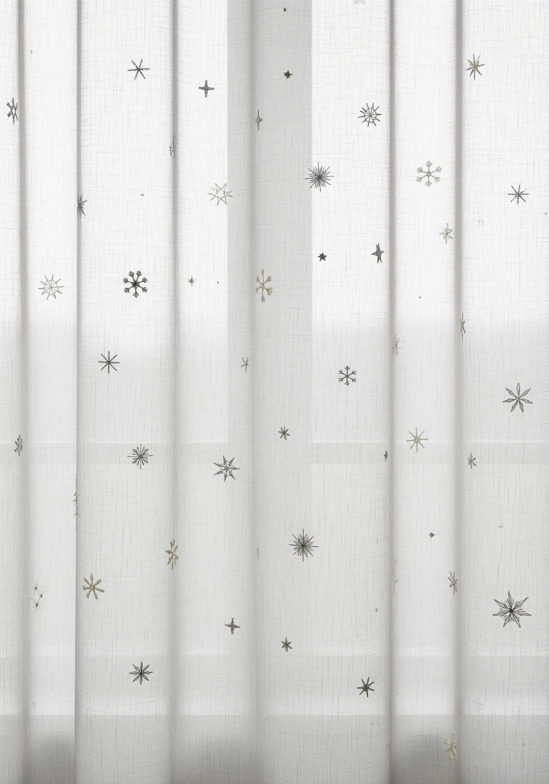 Sheer white curtains lightly embroidered with small, scattered silver and white snowflake motifs.
