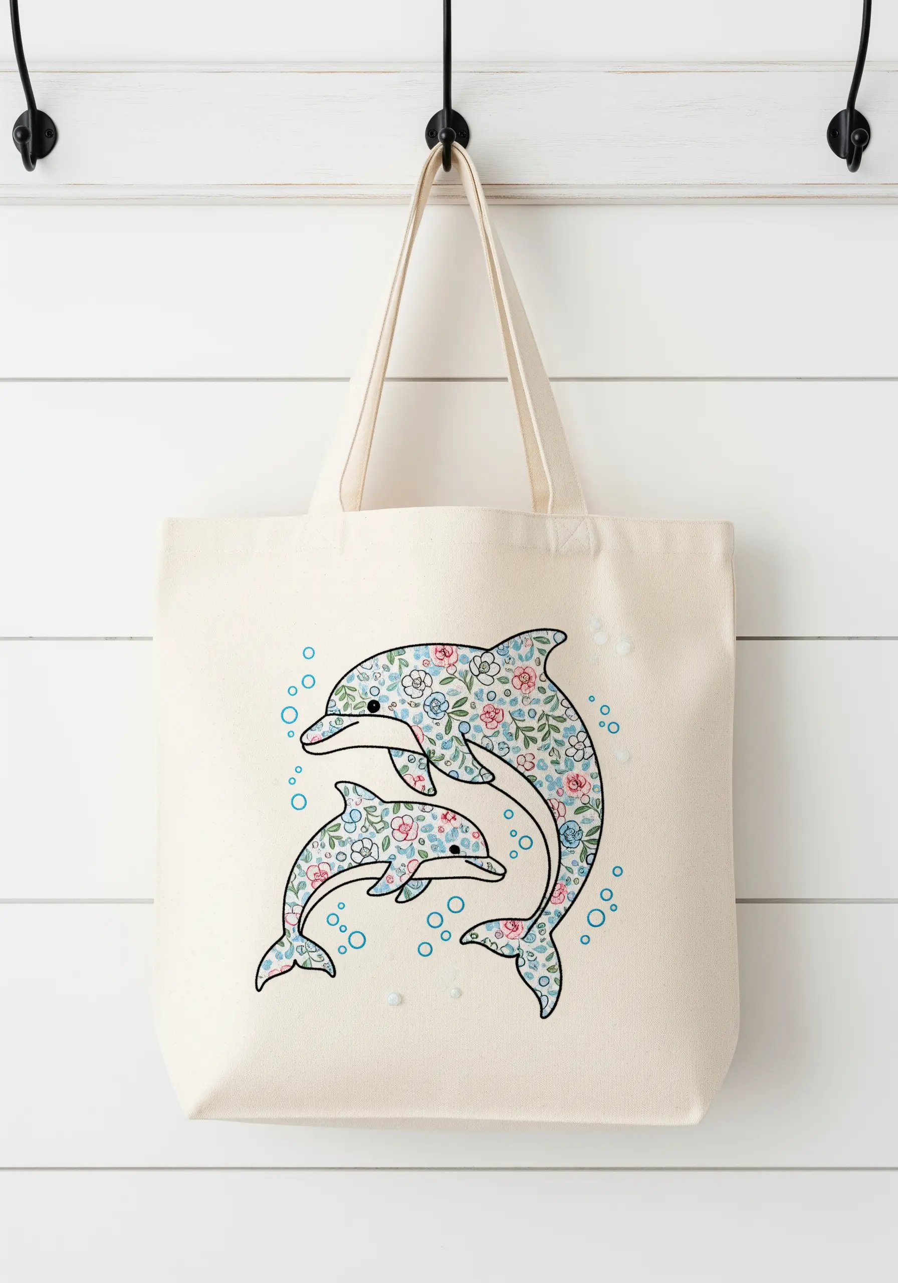 Two dolphins filled with a tiny floral pattern embroidered on a canvas tote bag.