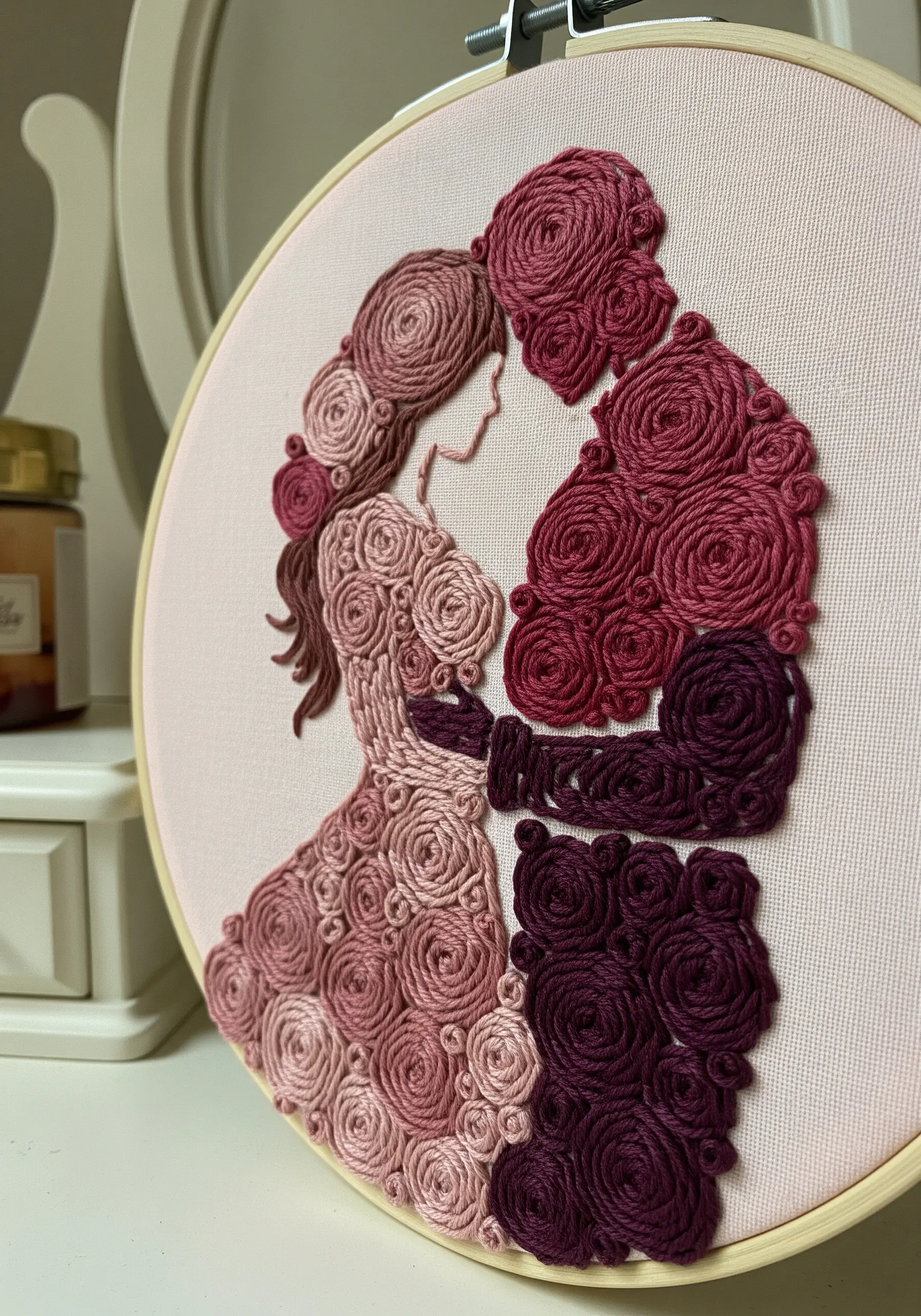 A couple's silhouette filled entirely with pink and burgundy woven wheel roses.