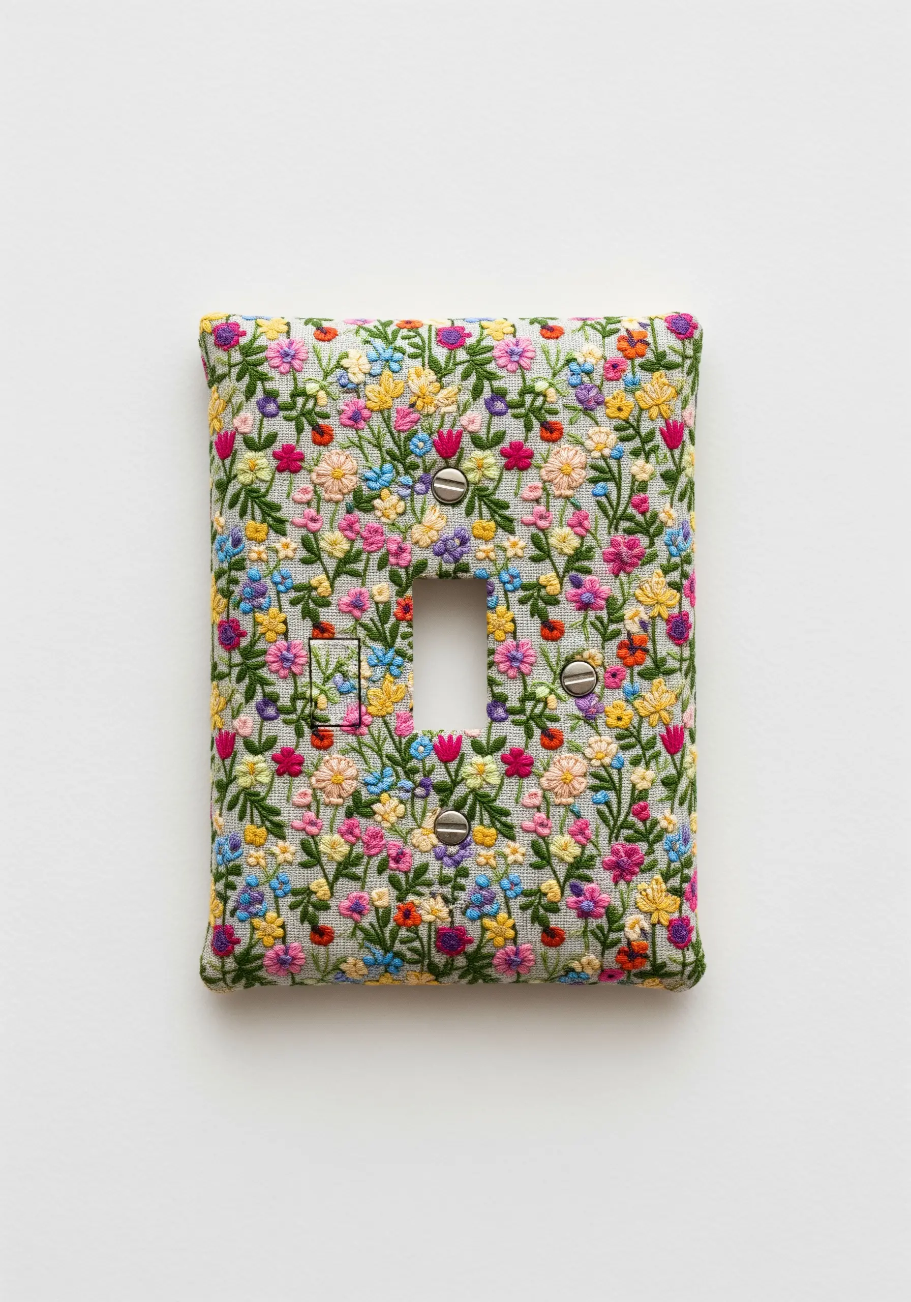 A light switch cover completely covered in a dense, colorful floral embroidery pattern.