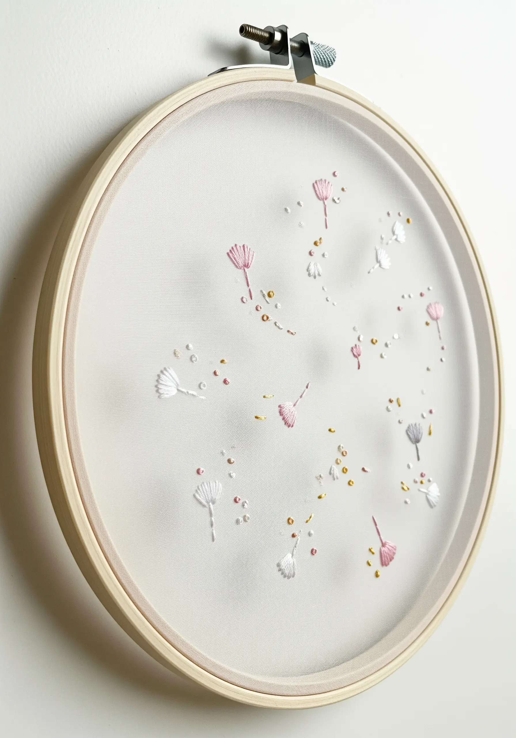Delicate dandelion seeds embroidered with metallic accents on a sheer, transparent fabric.