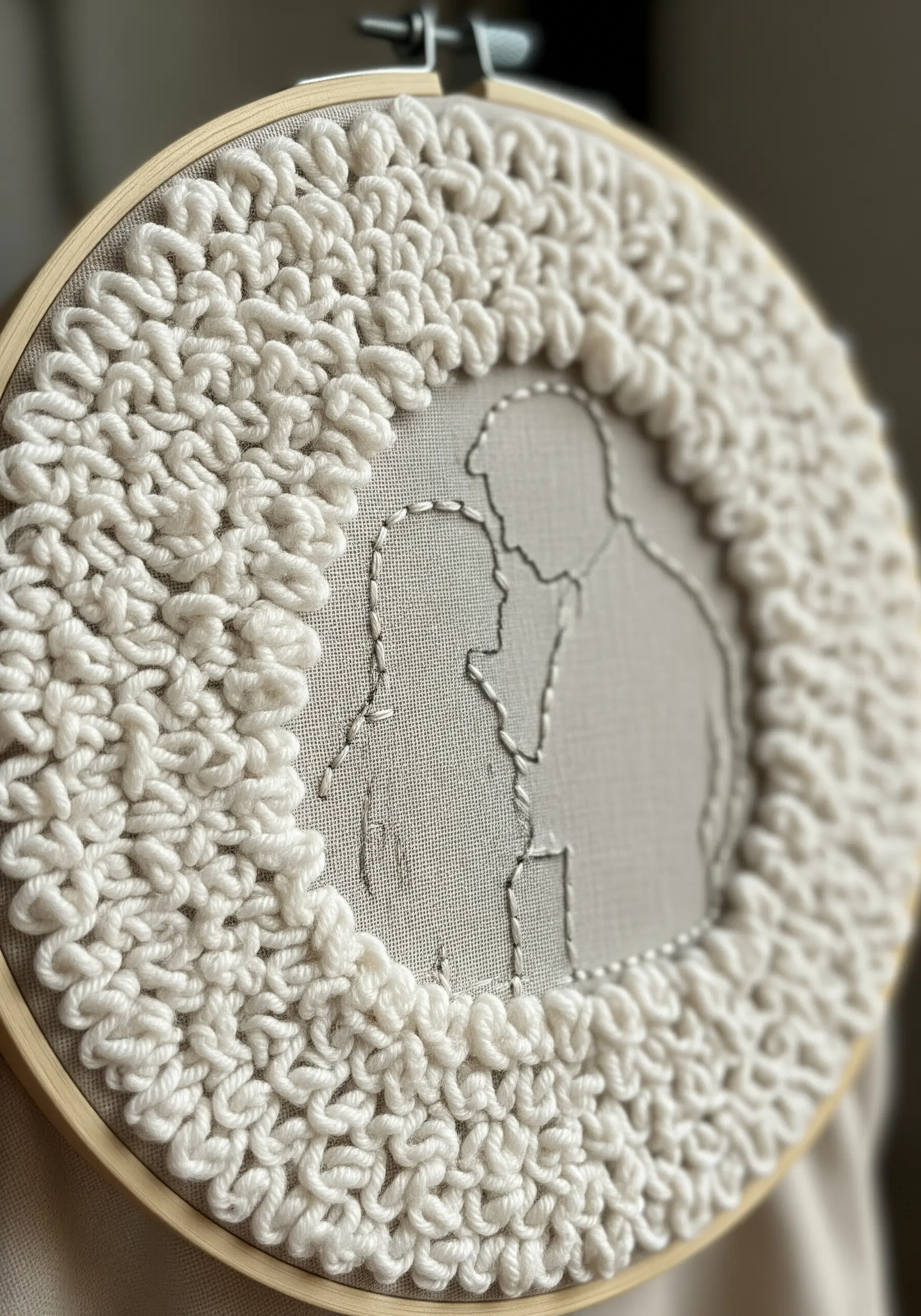 A simple backstitched couple silhouette framed by a thick, loopy white yarn border.