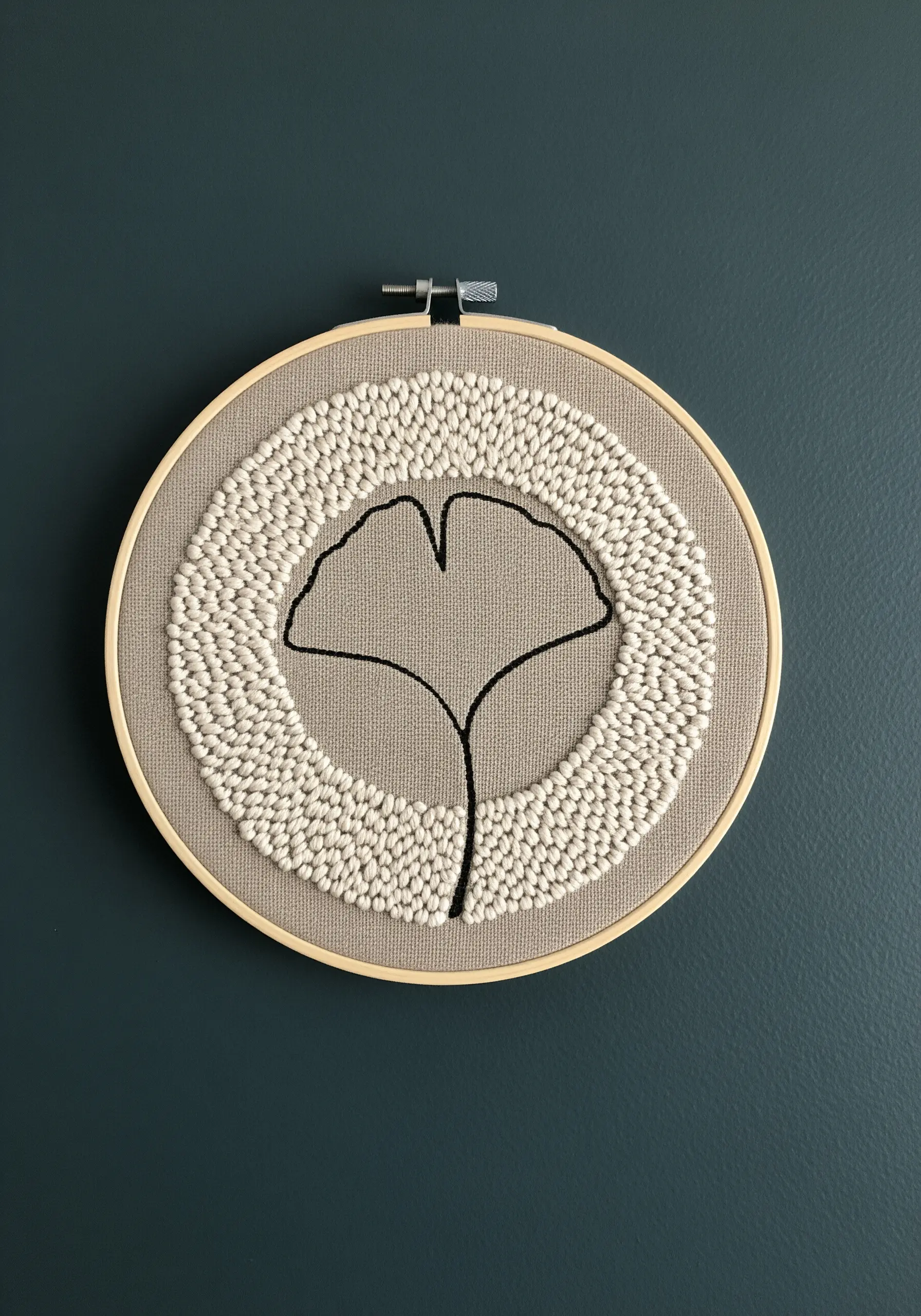 A ginkgo leaf outline surrounded by a dense circle of ivory seed stitches.