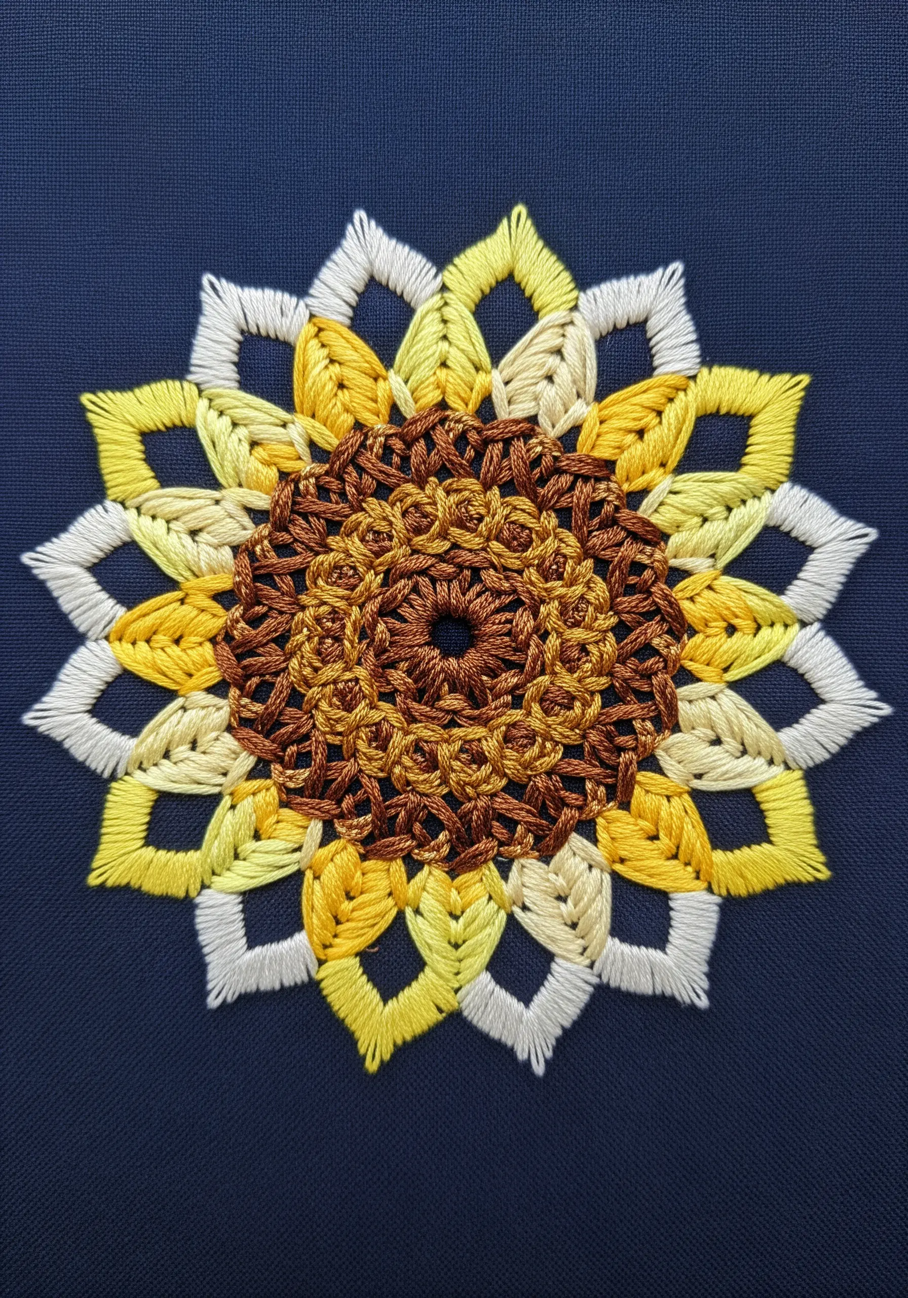 A geometric sunflower mandala with open, looped stitches in white, yellow, and brown.