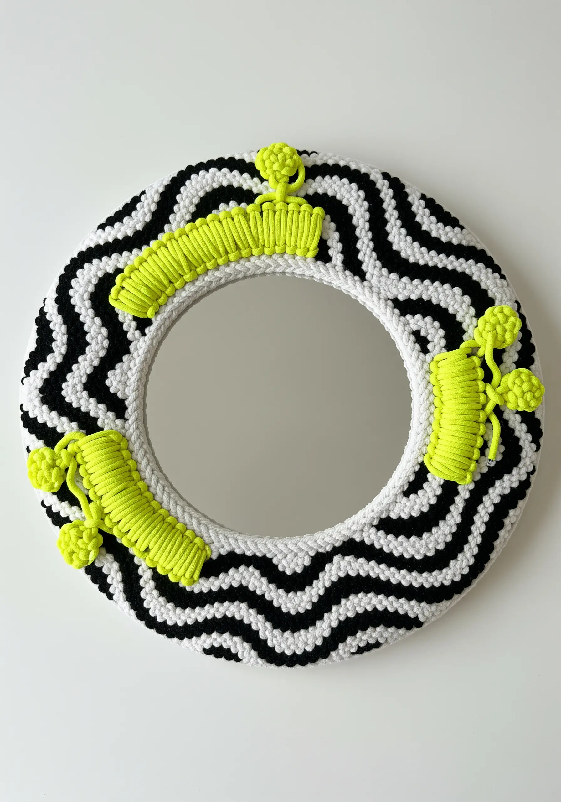 A round mirror framed with black-and-white chevron weaving and neon yellow accents.