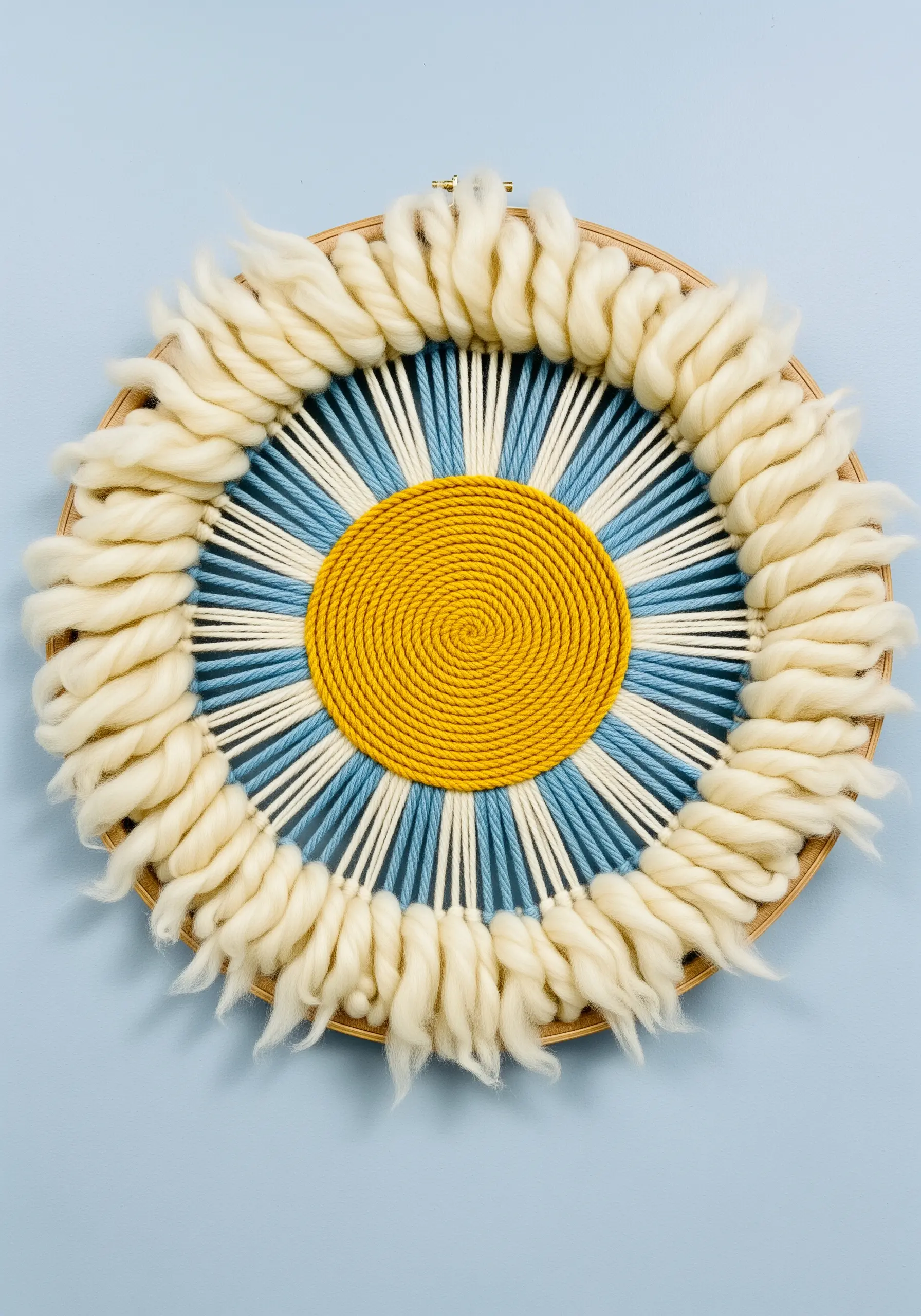Circular woven art in a hoop with a fluffy, unspun wool roving border.