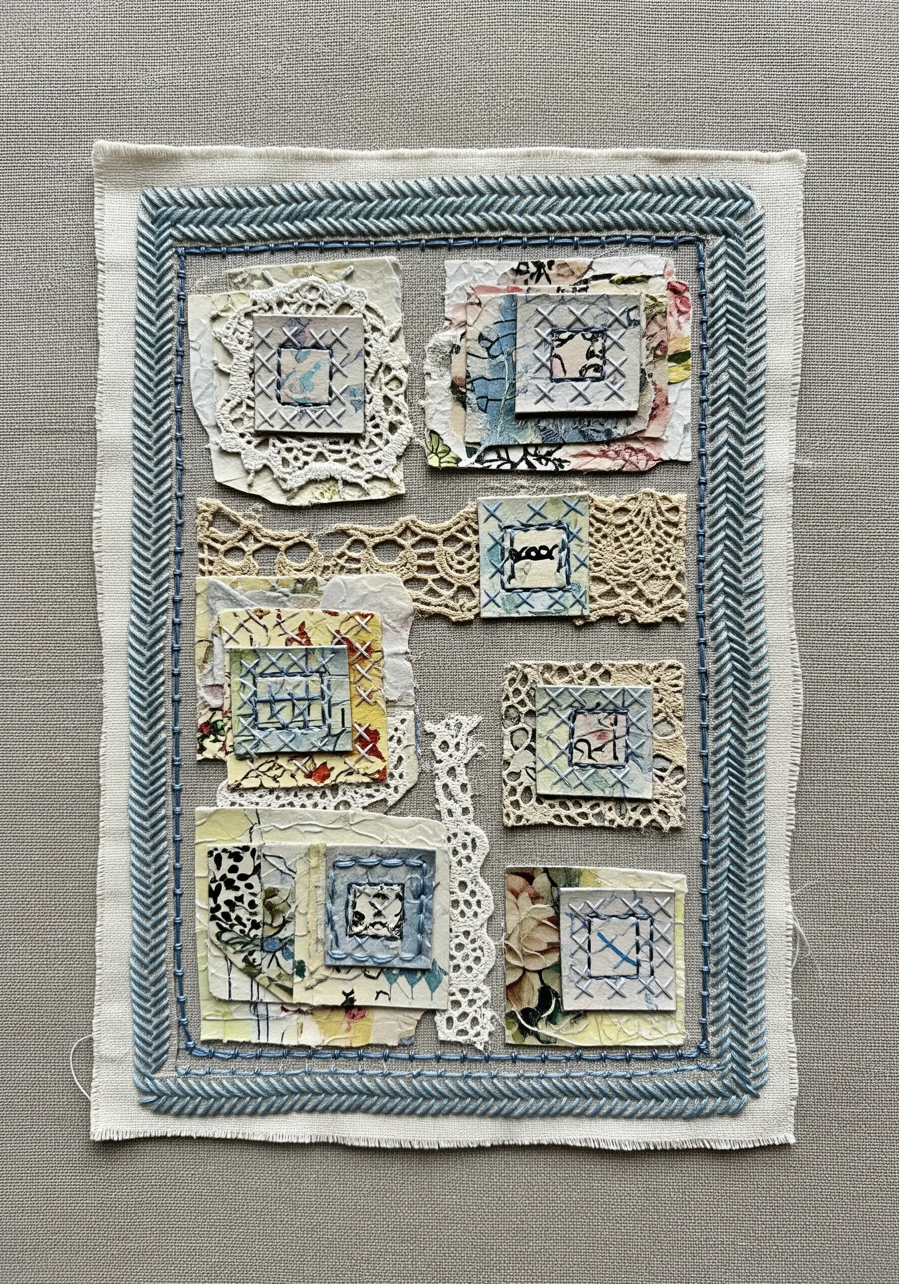 A fabric and paper collage framed with a bold blue herringbone stitch border.