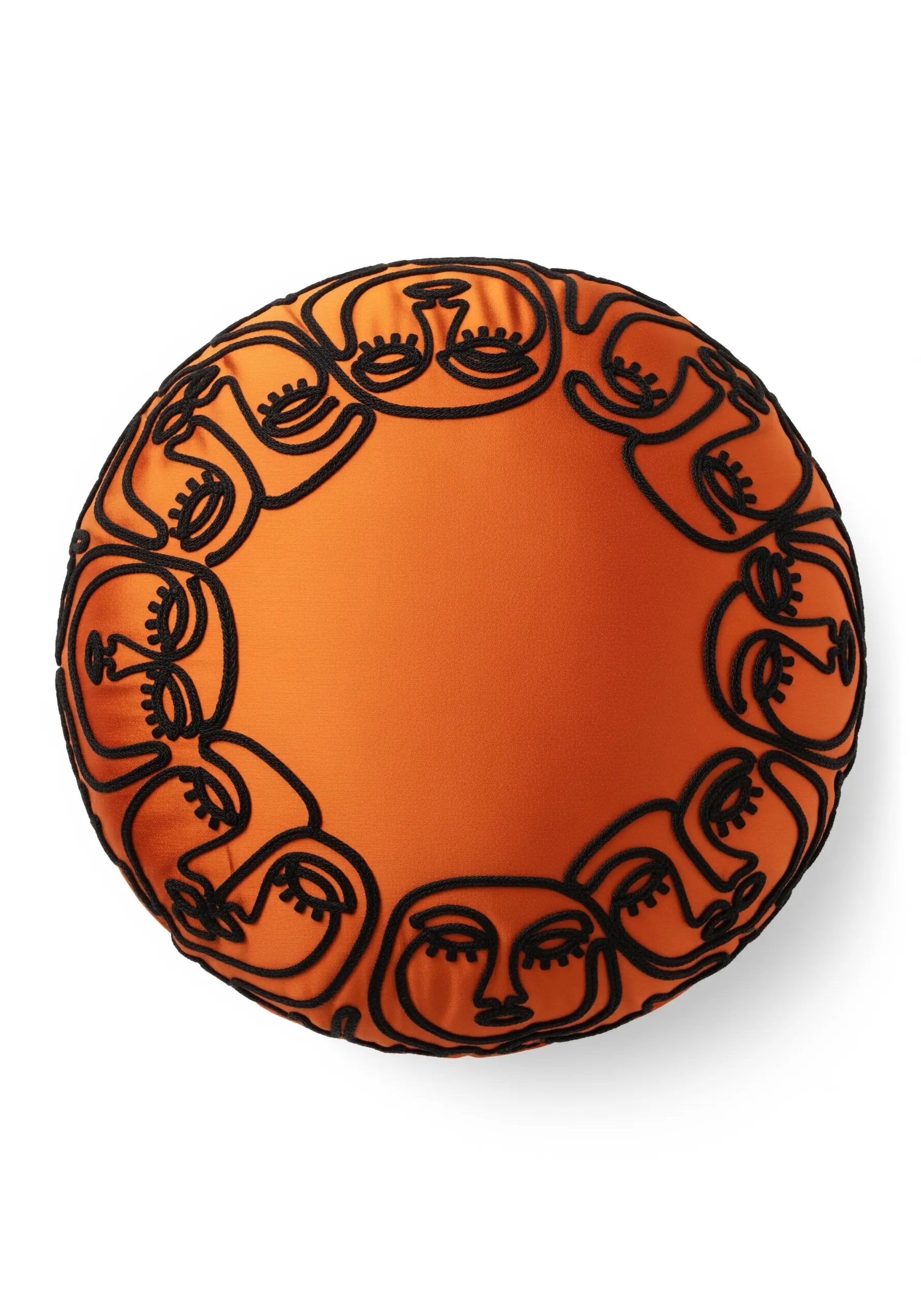 A circular border of abstract faces in black cord on a bright orange round cushion