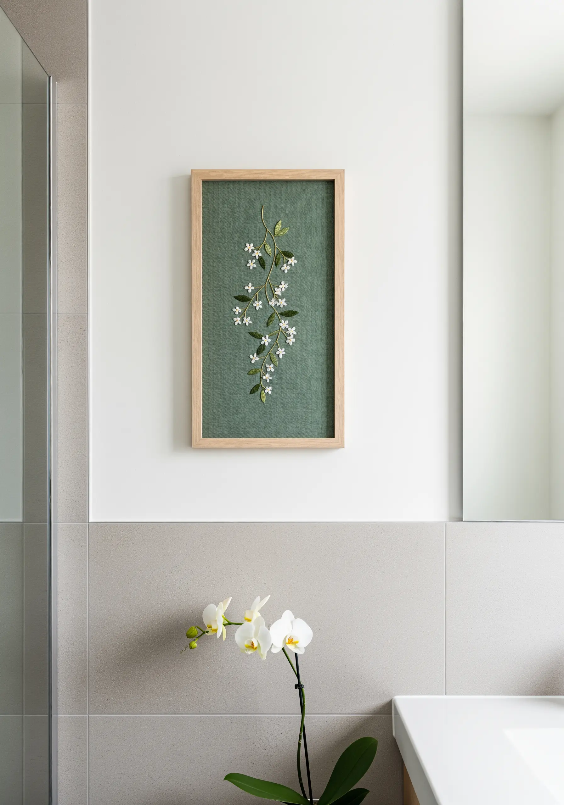 Embroidered white jasmine vine on dark green fabric presented in a rectangular wooden frame.