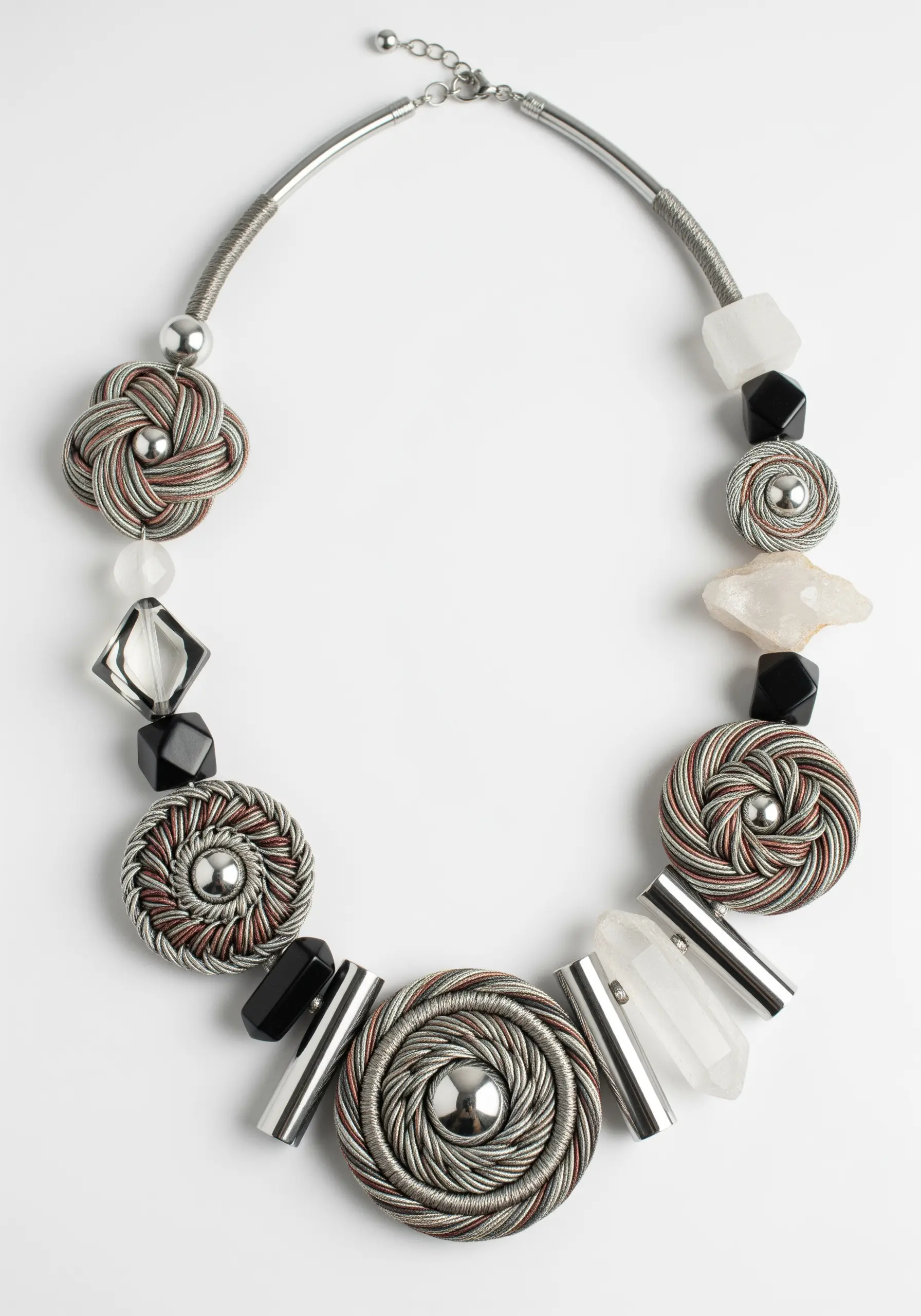 A statement necklace combining thread-wrapped medallions, metal beads, and raw crystals.