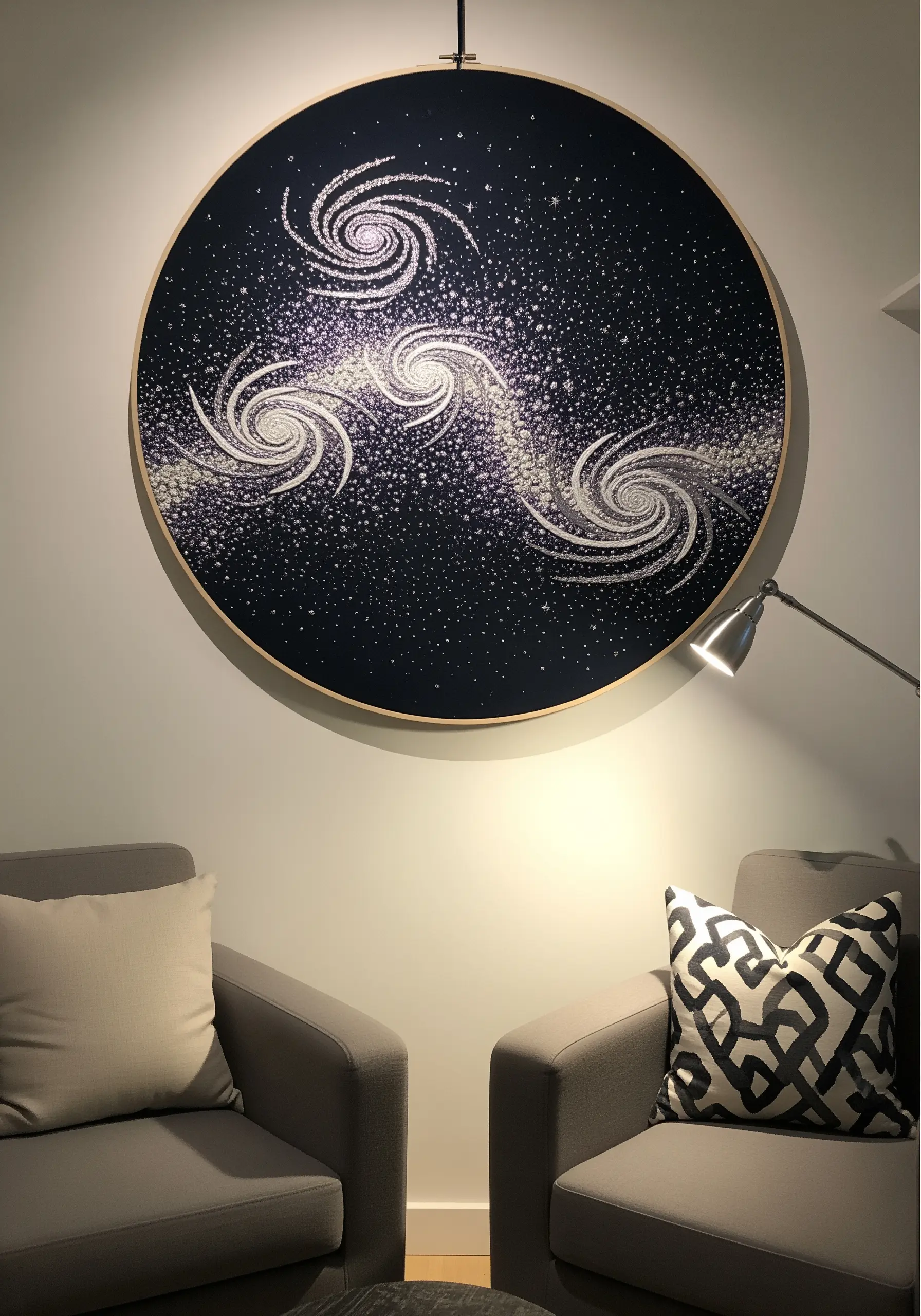 Large embroidery hoop depicting swirling galaxies on a dark background using seed stitches and French knots.