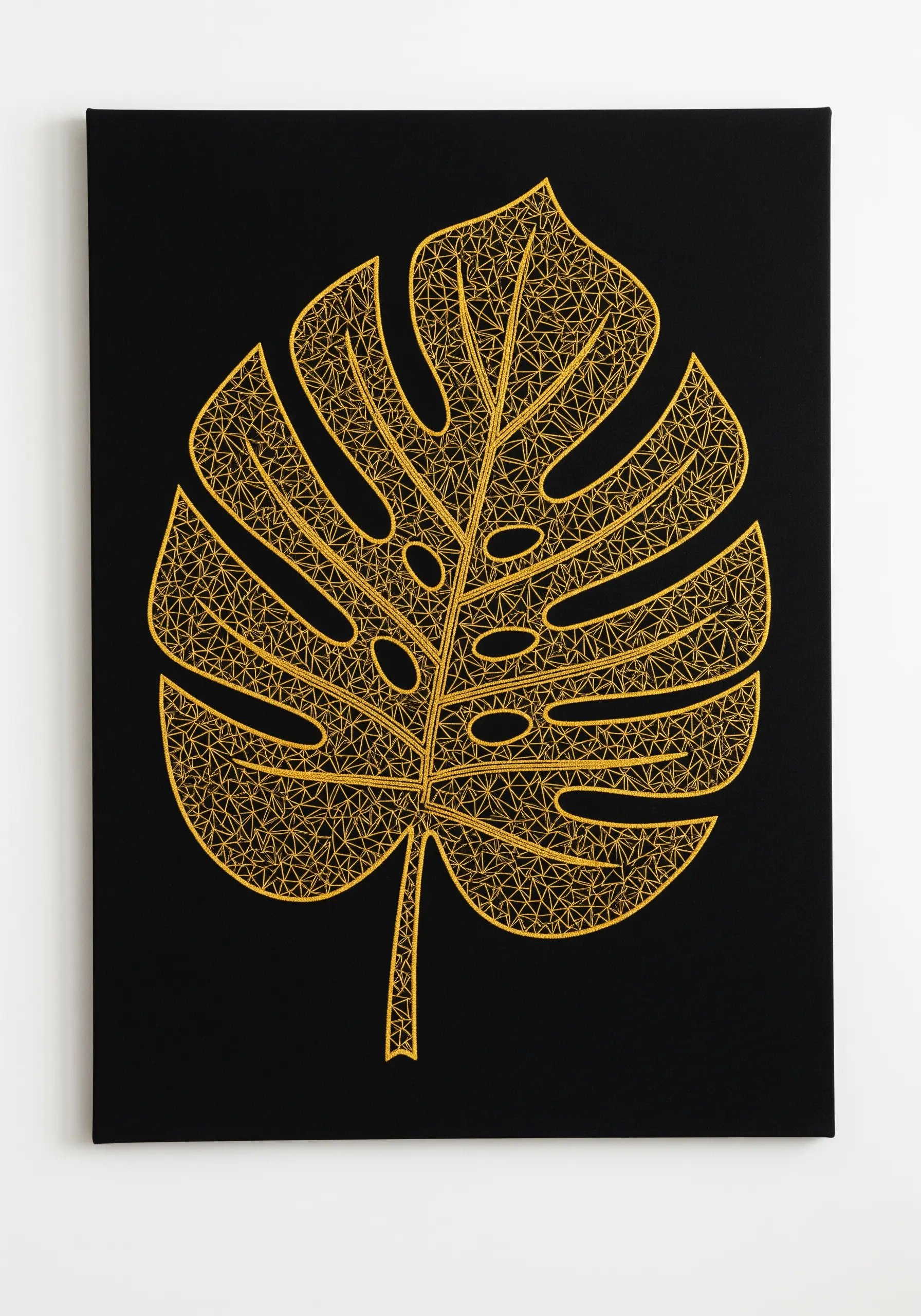 A monstera leaf outlined in gold thread and filled with a geometric gold mosaic pattern.