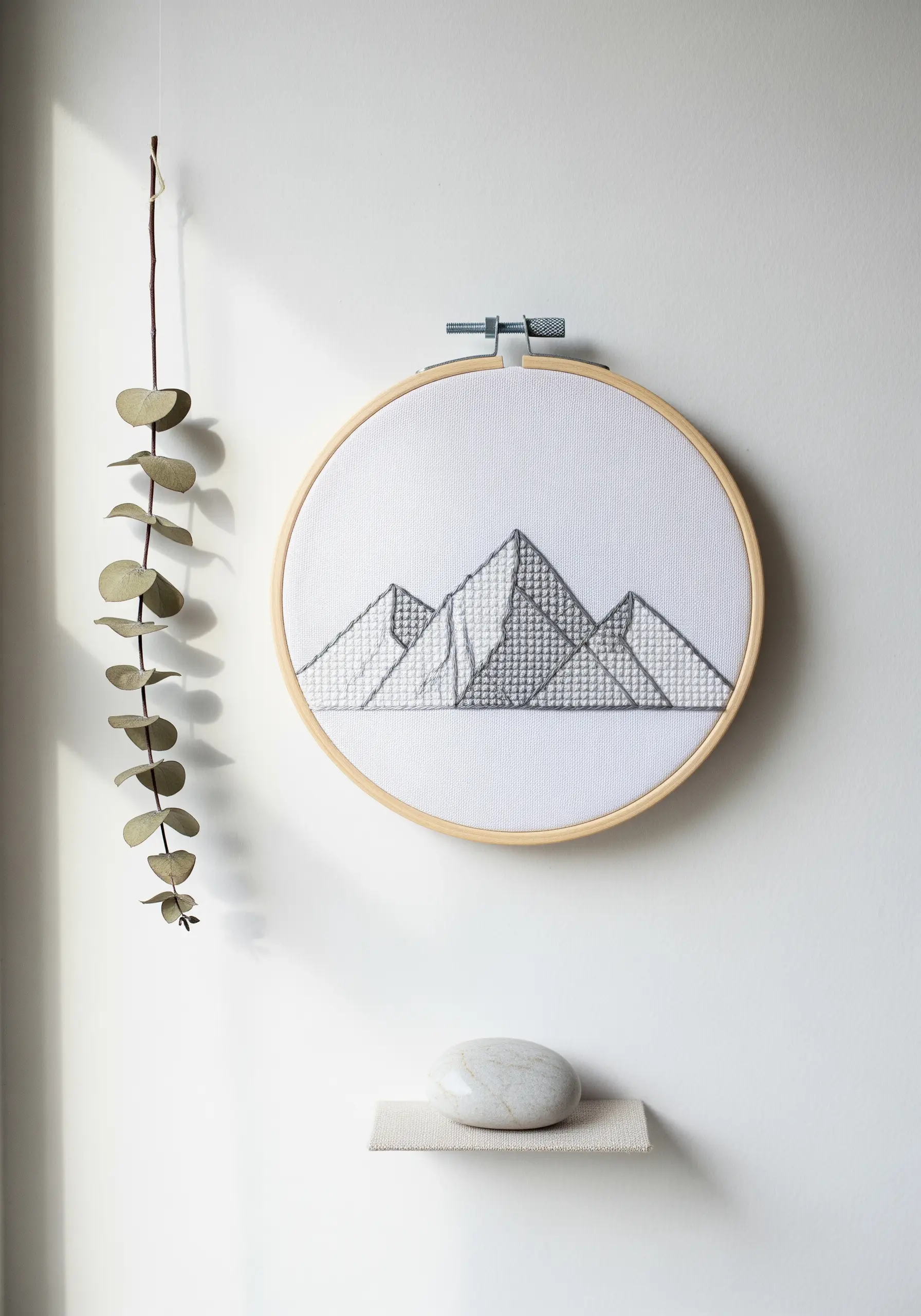 Geometric mountain range with grey thread fill stitches on white fabric.