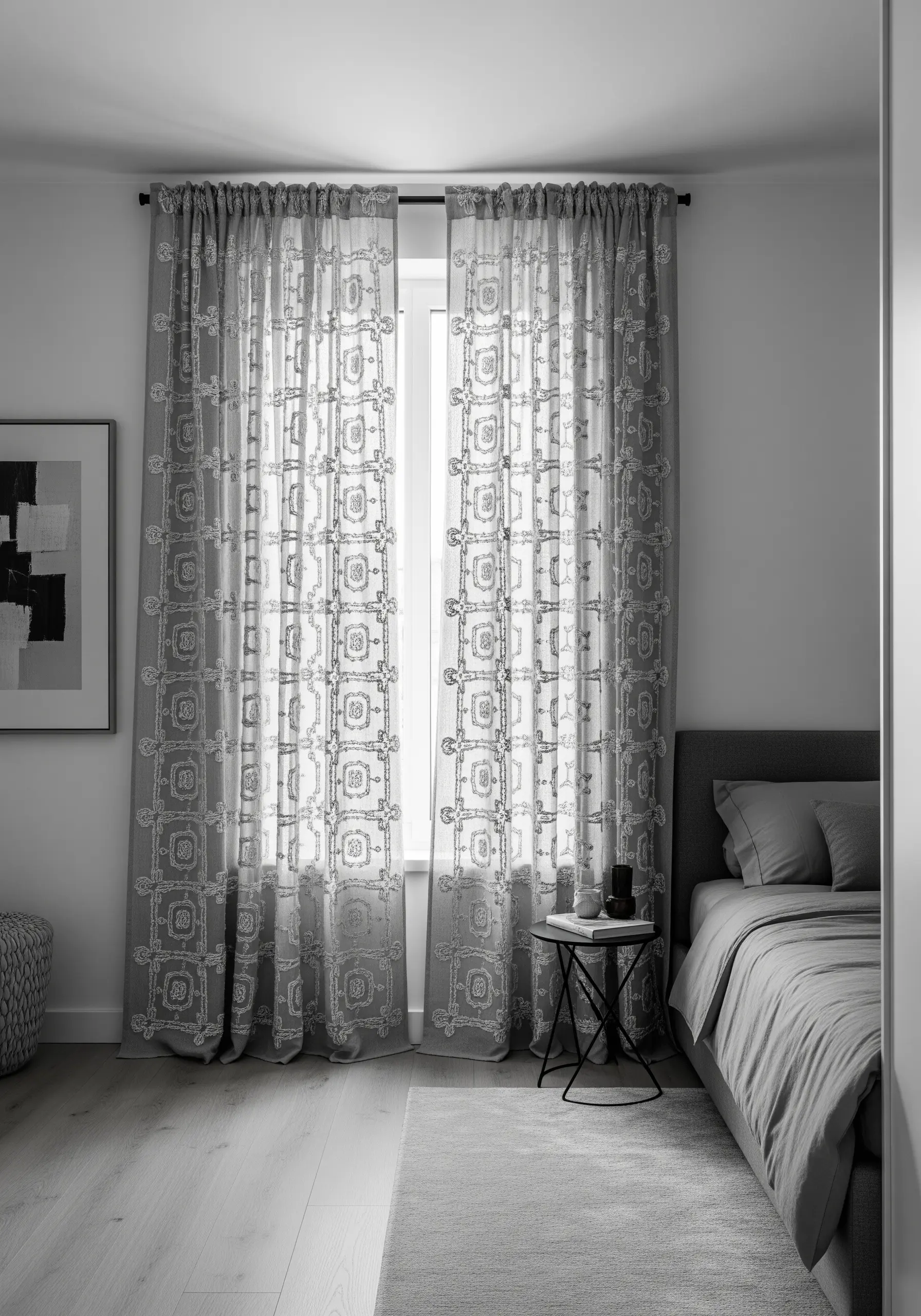 White geometric pattern embroidered on sheer grey curtains in a monochrome bedroom.