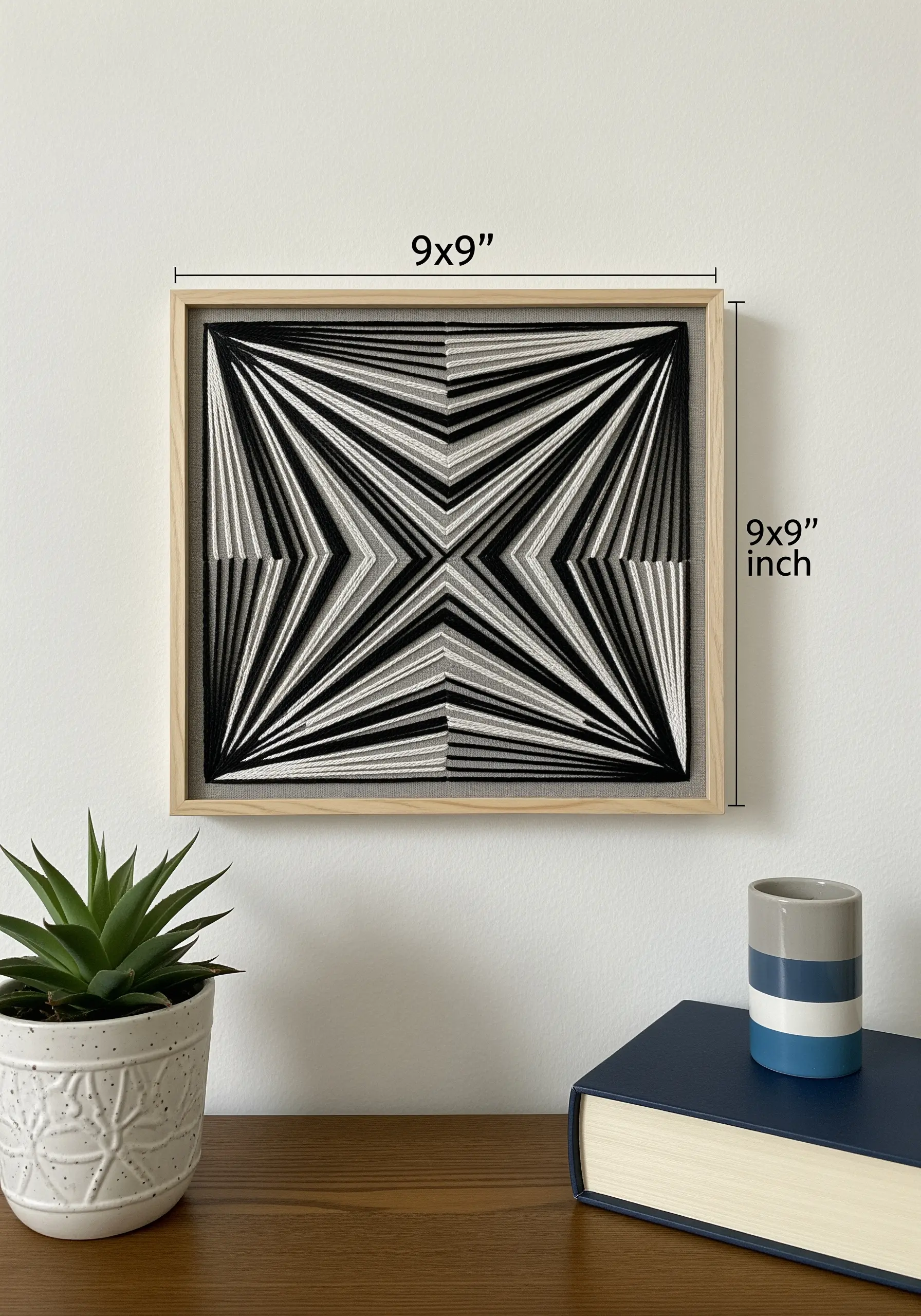 A framed 3D string art embroidery piece with a geometric starburst in black, white, and gray.
