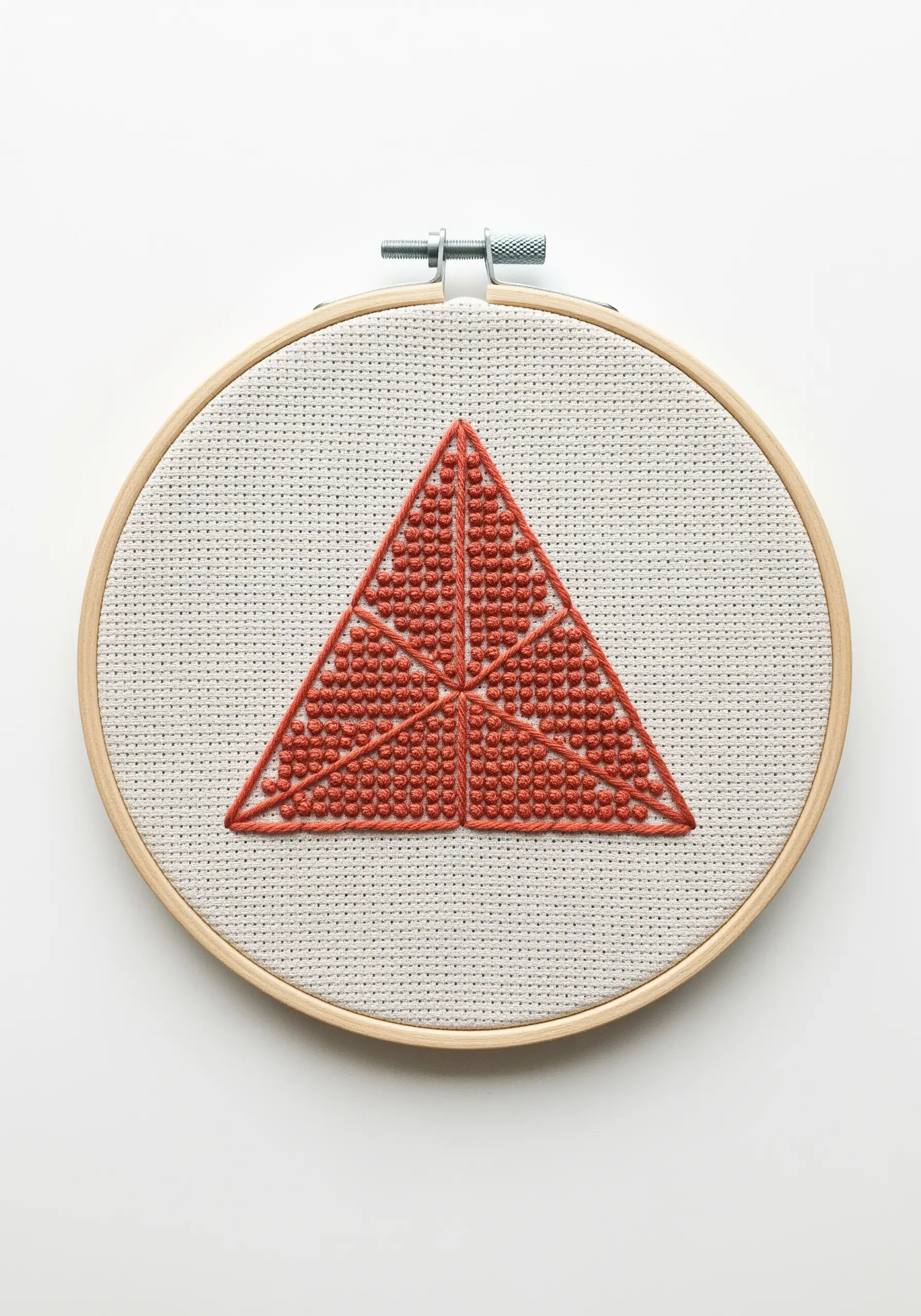 Triangle filled with red-orange French knots on Aida cloth.