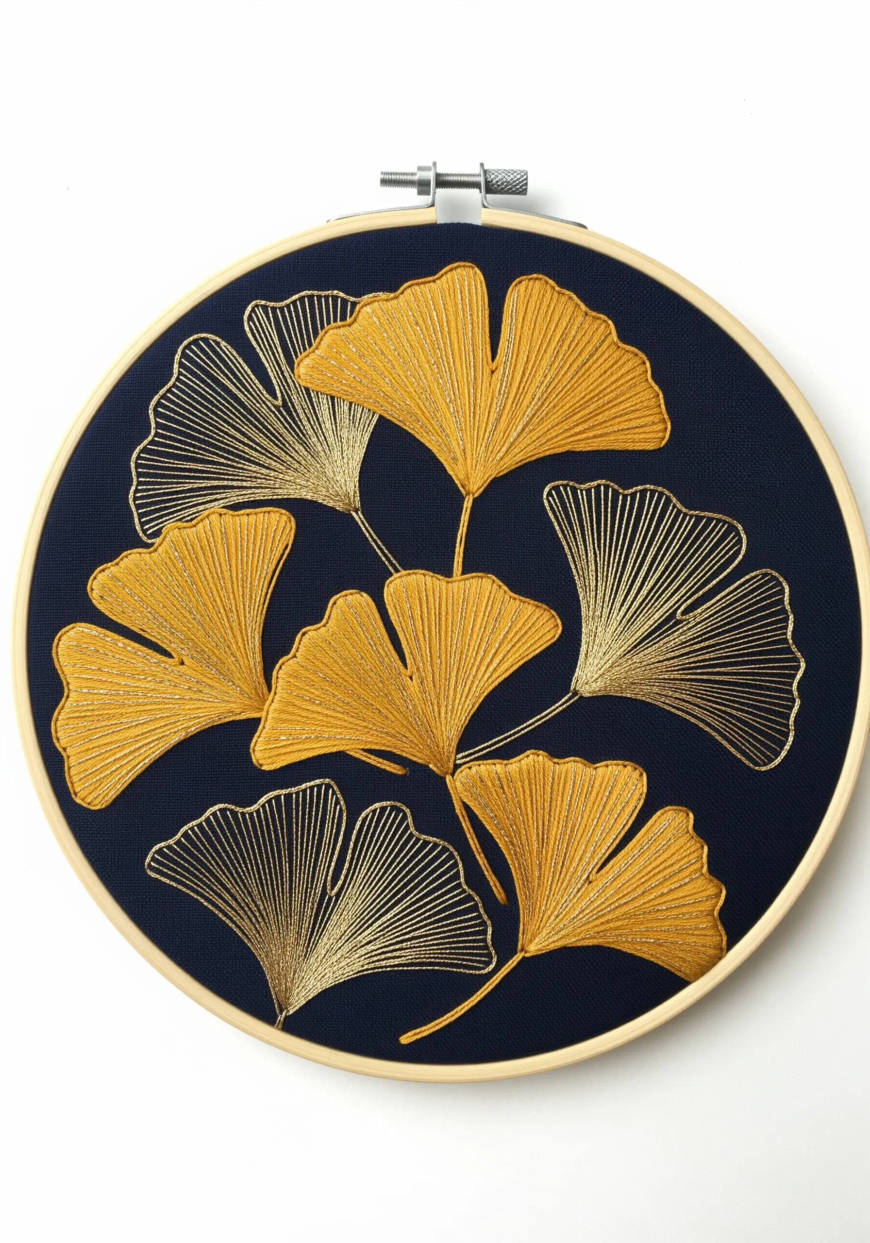 A cluster of ginkgo leaves embroidered in gold and metallic thread on dark blue fabric.