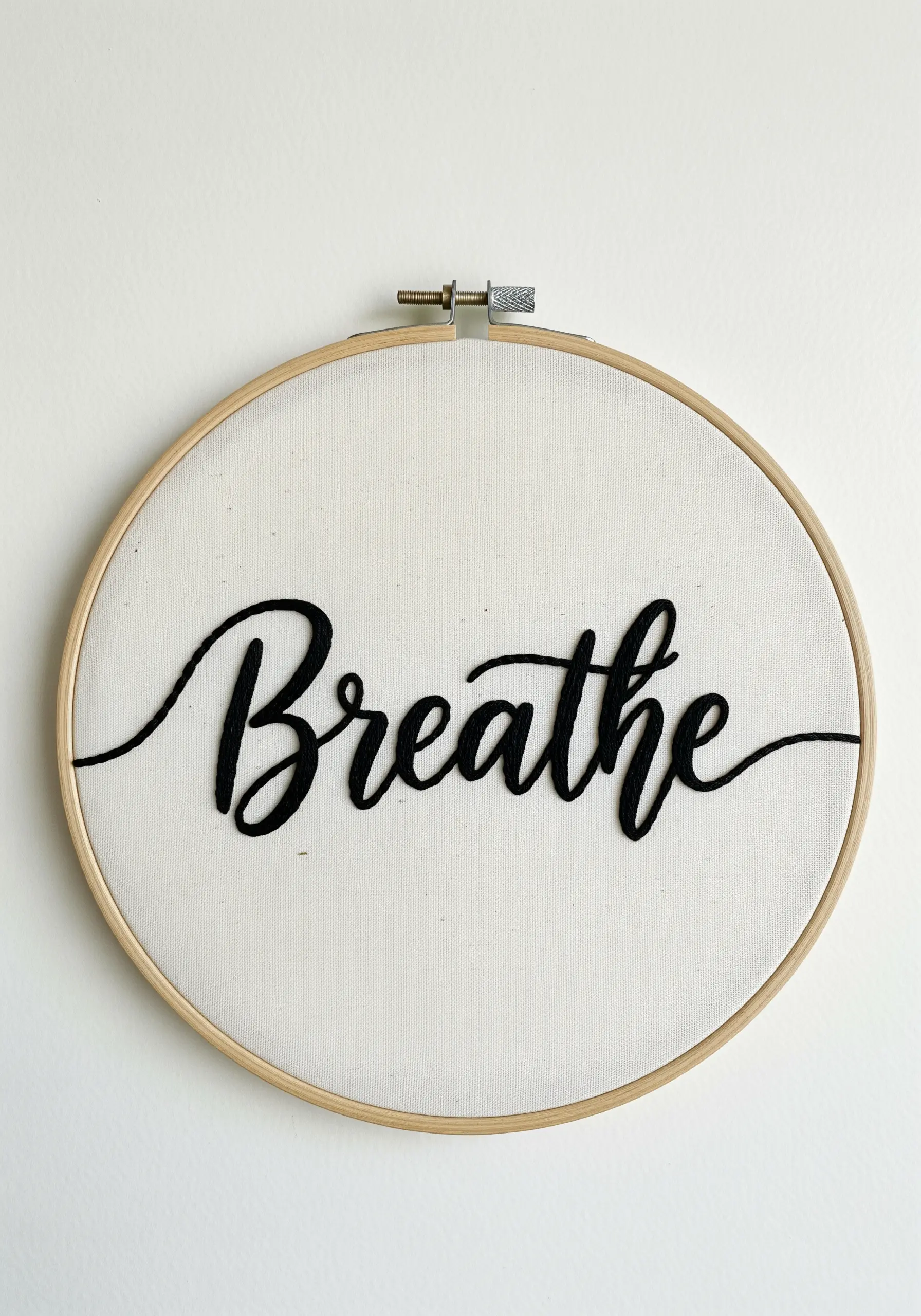The word 'Breathe' embroidered in thick, raised black cursive script on white canvas.