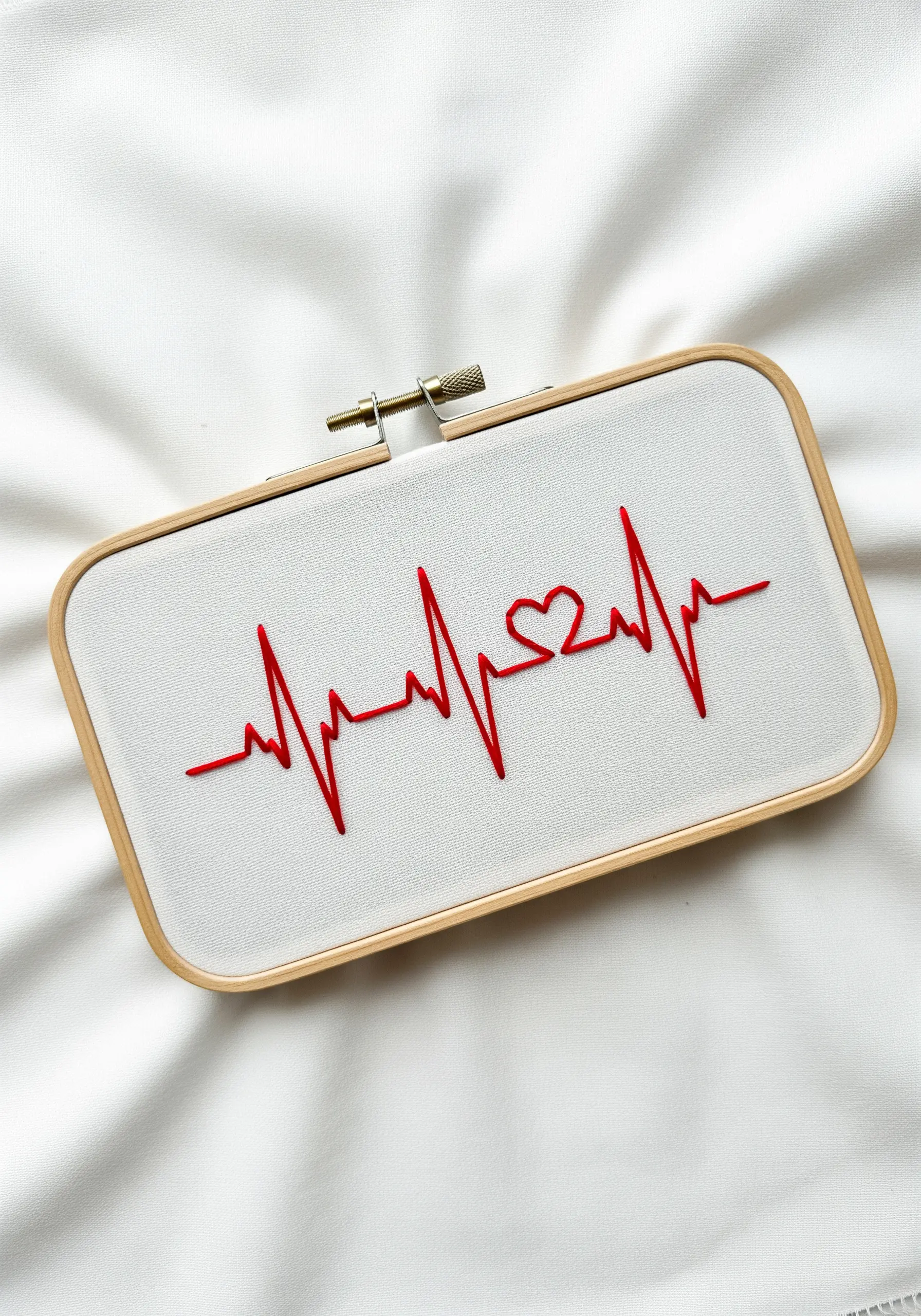 A heartbeat line with a heart in the center, embroidered in red stem stitch.