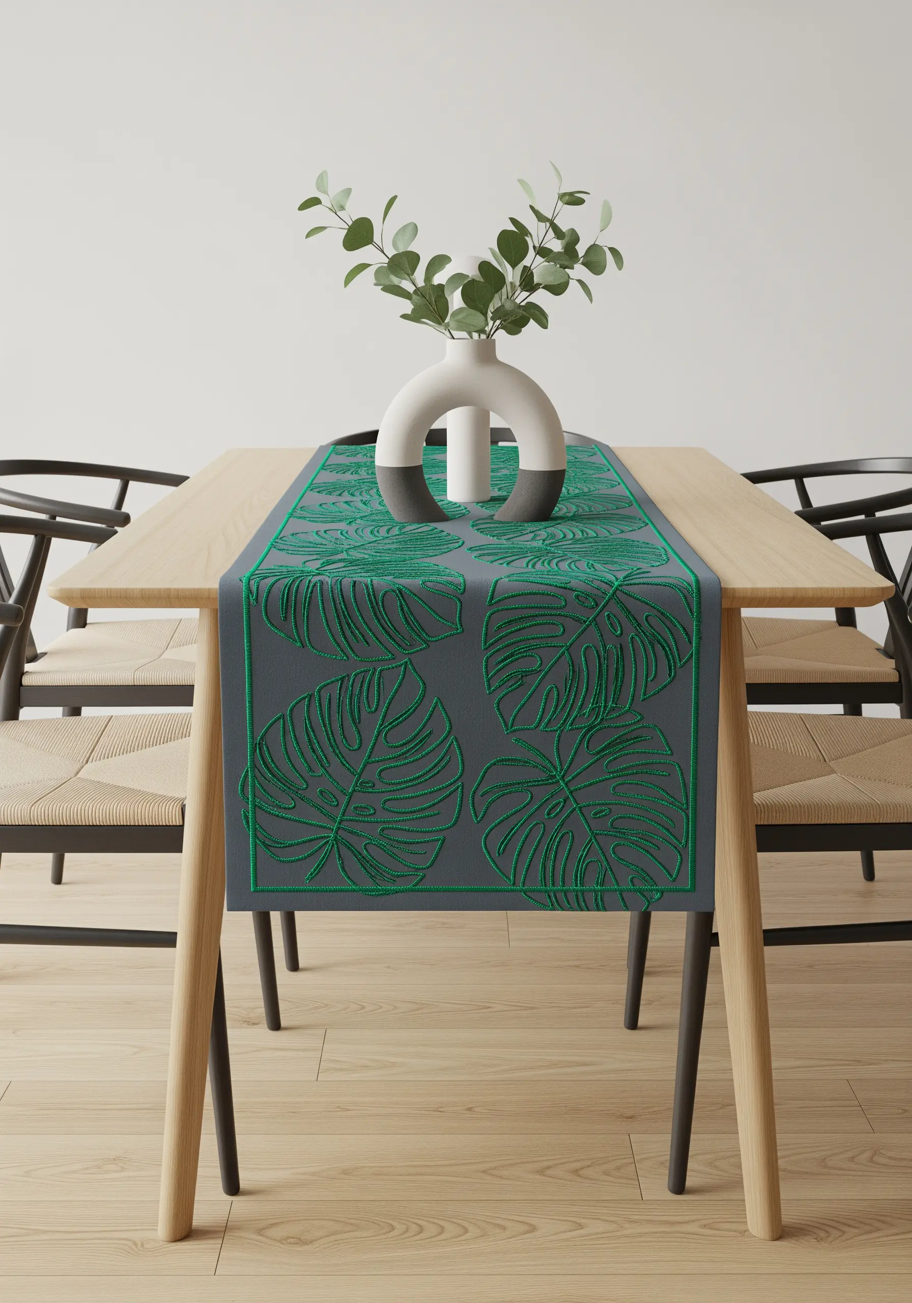 Modern table runner with bold, green outline embroidery of Monstera leaves.