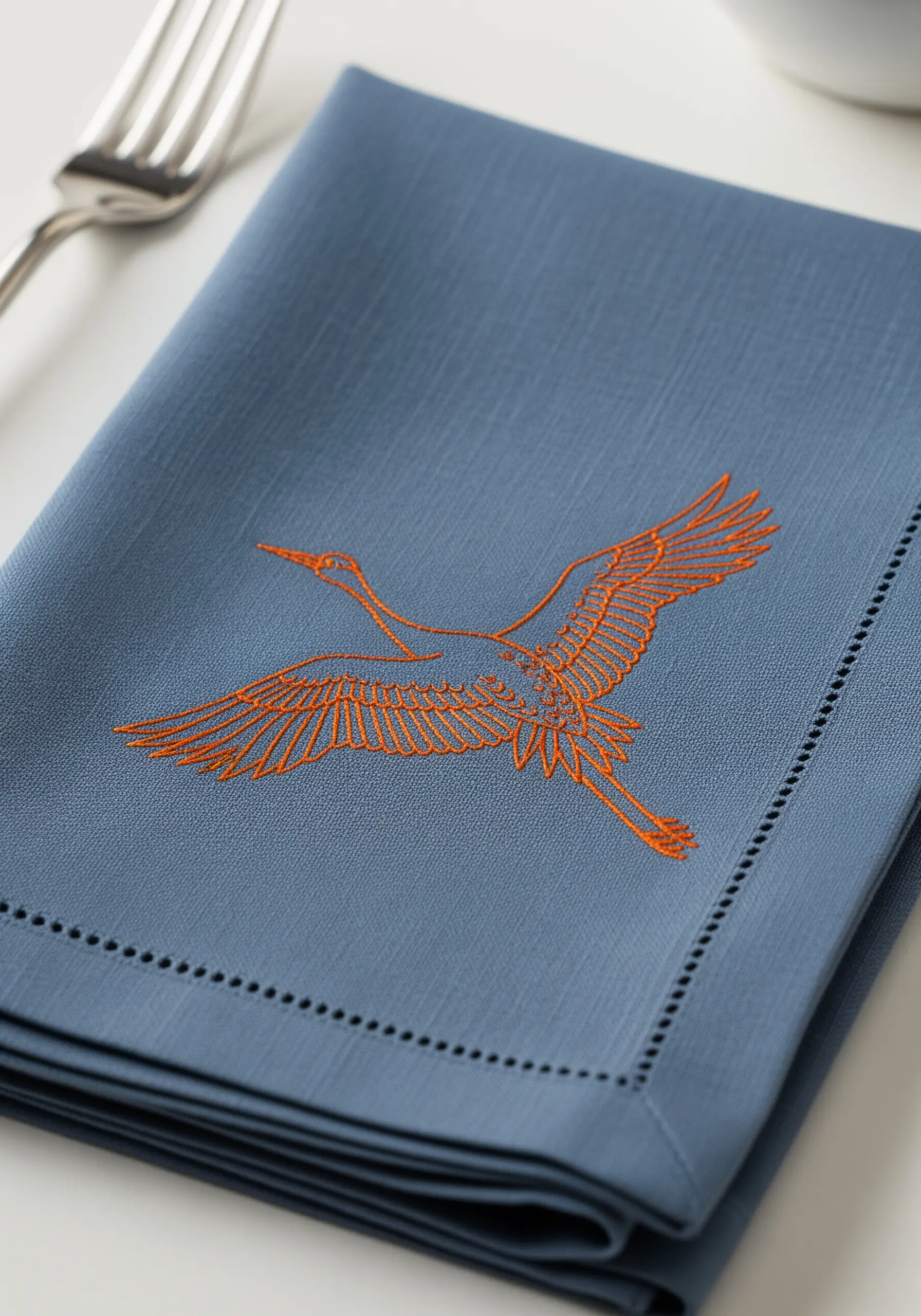 A detailed line art embroidery of a crane in flight, stitched in orange.