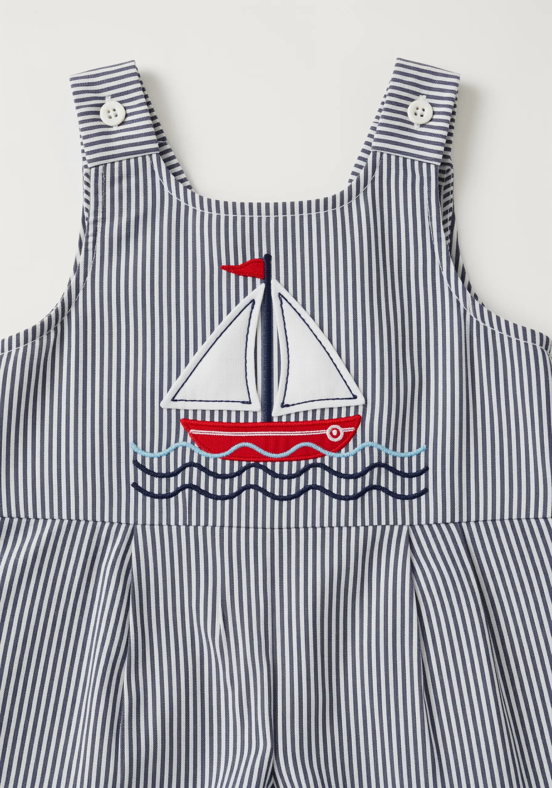 Appliqué sailboat with embroidered details on a blue-and-white striped romper.