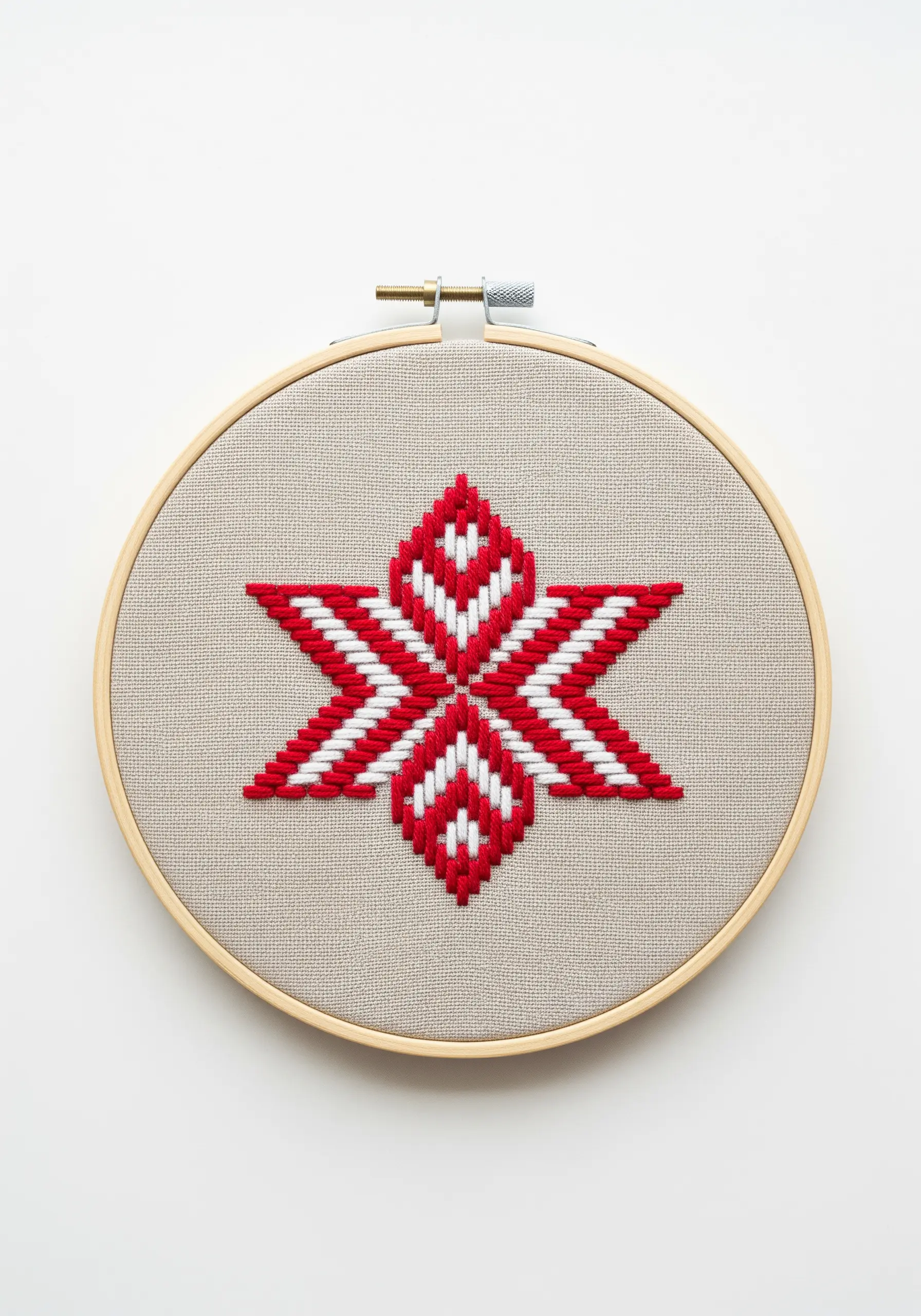 A red and white geometric star stitched in a Bargello style on canvas fabric.