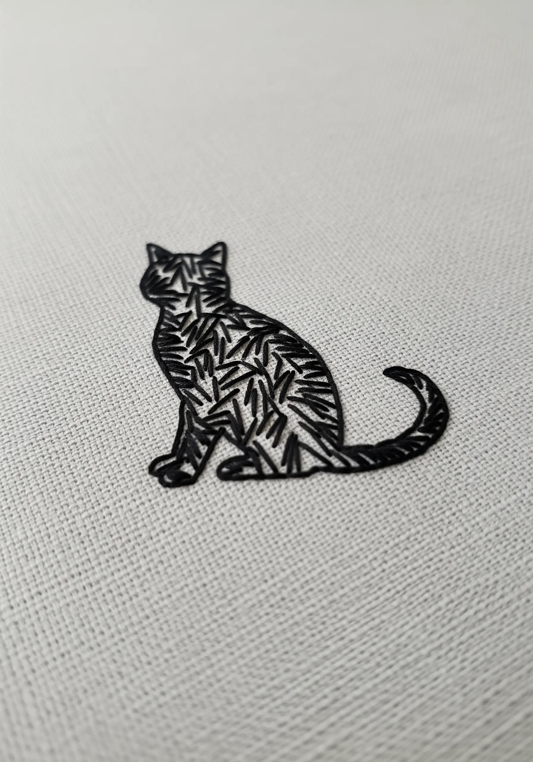 A black cat silhouette filled with a dynamic pattern of short straight stitches.
