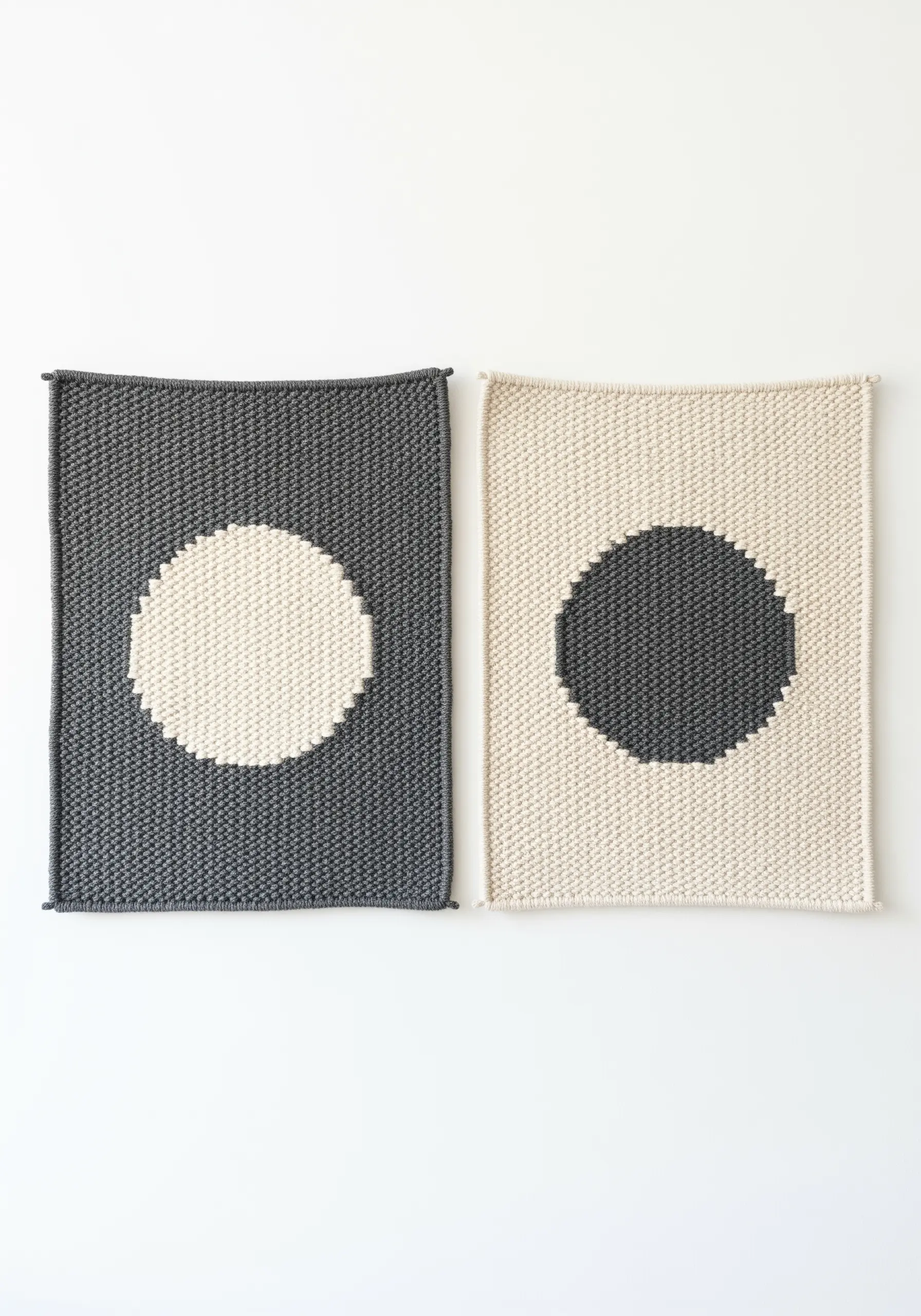 Two knitted rectangular panels, one dark grey with a cream circle and one cream with a dark grey circle.