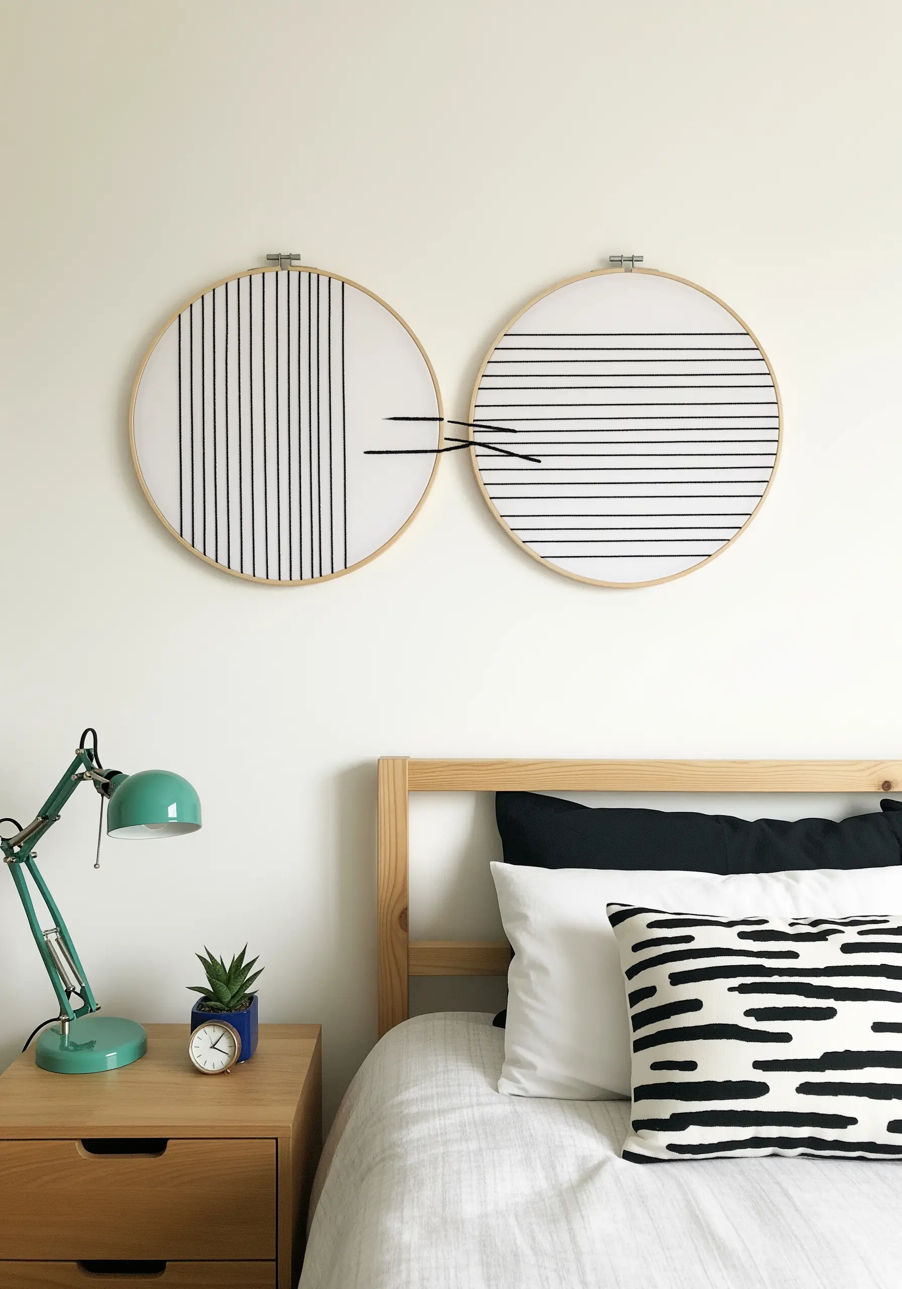 Two embroidery hoops with bold black vertical and horizontal lines, connected by threads.