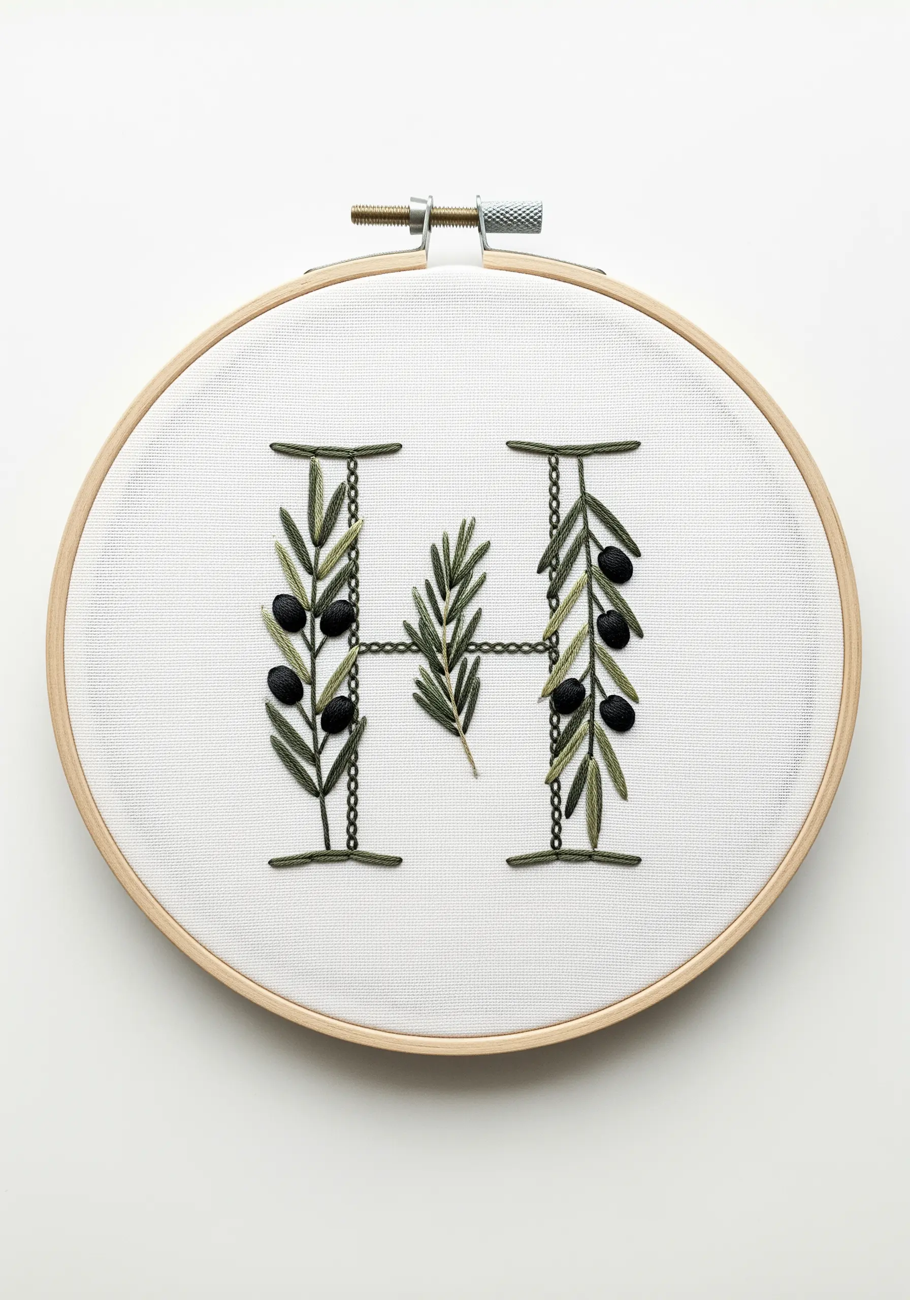 A minimalist letter H composed of olive branches with black olives against white fabric.